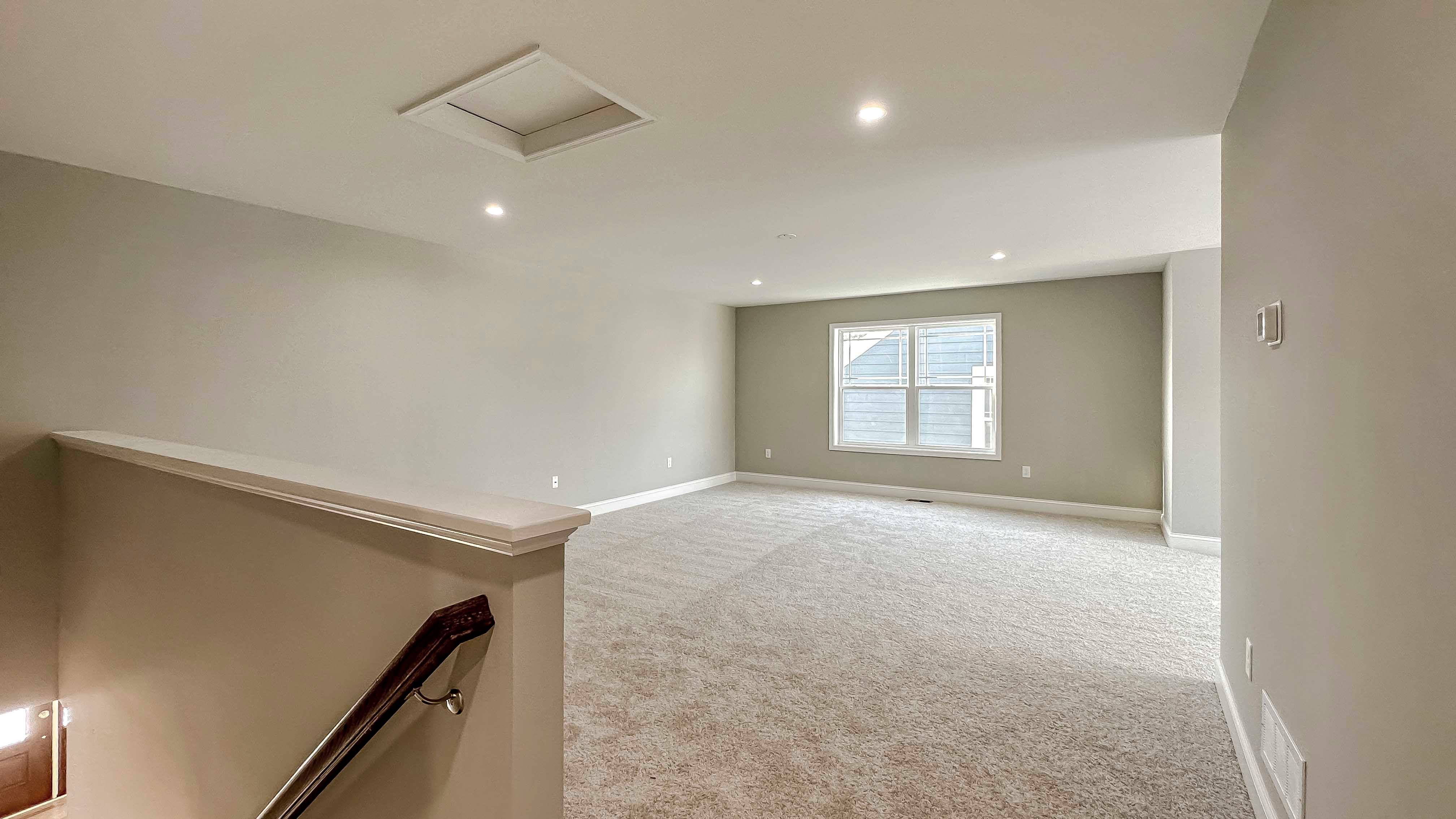 Loft area with carpet flooring and two windows on side wall