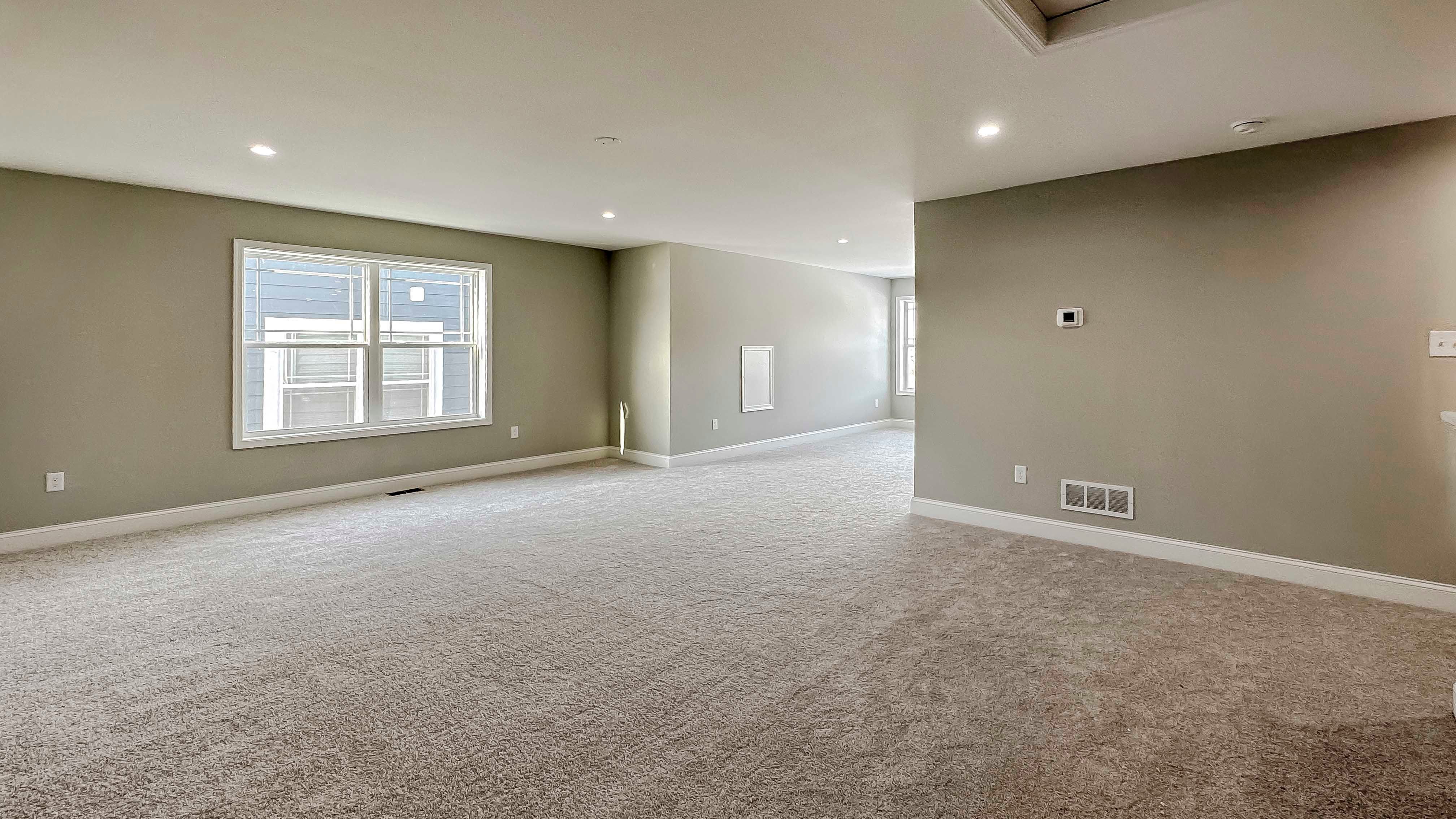 Loft area with carpet flooring and two windows on side wall