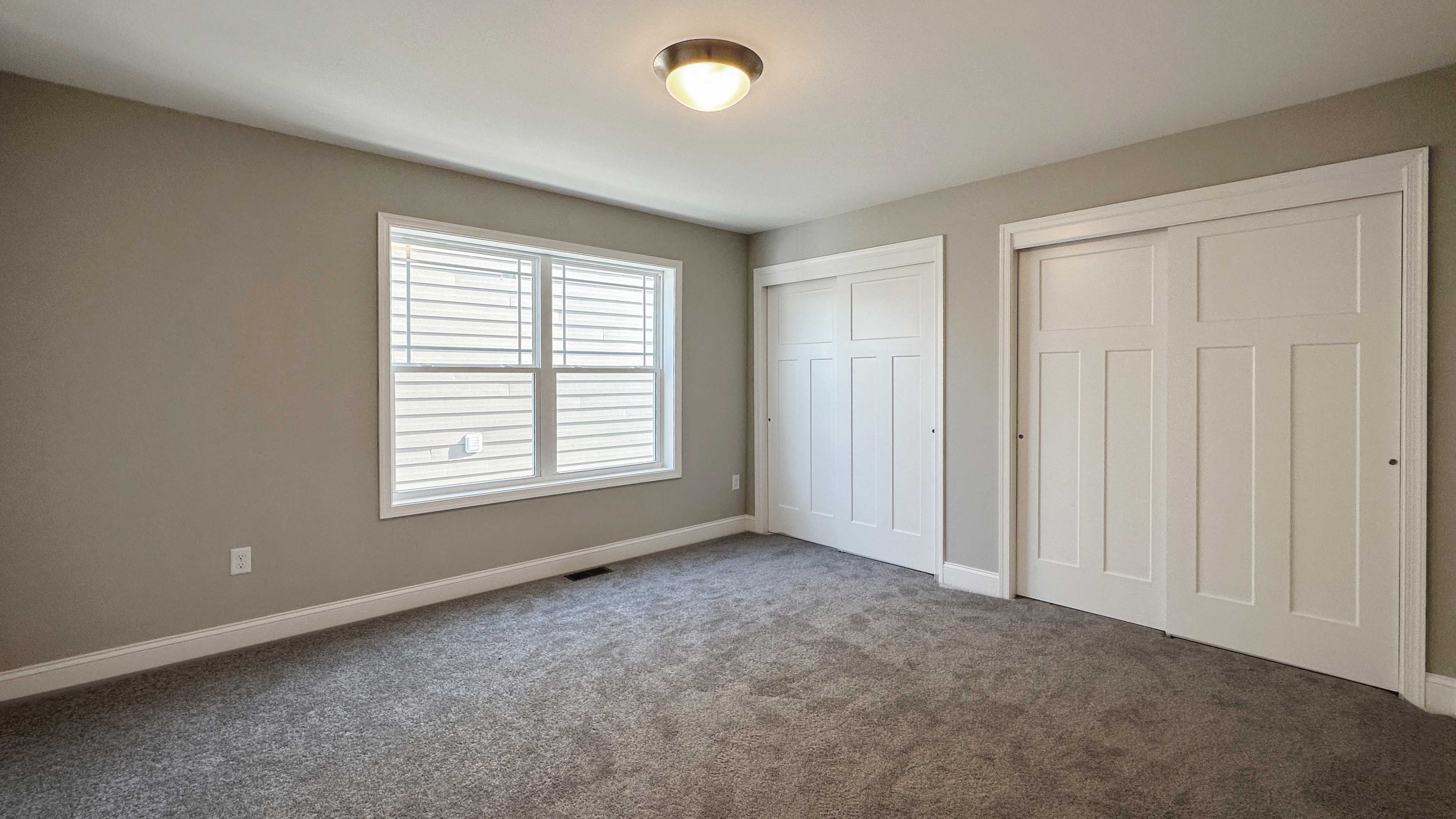Bedroom with dual closets and two windows on side wall