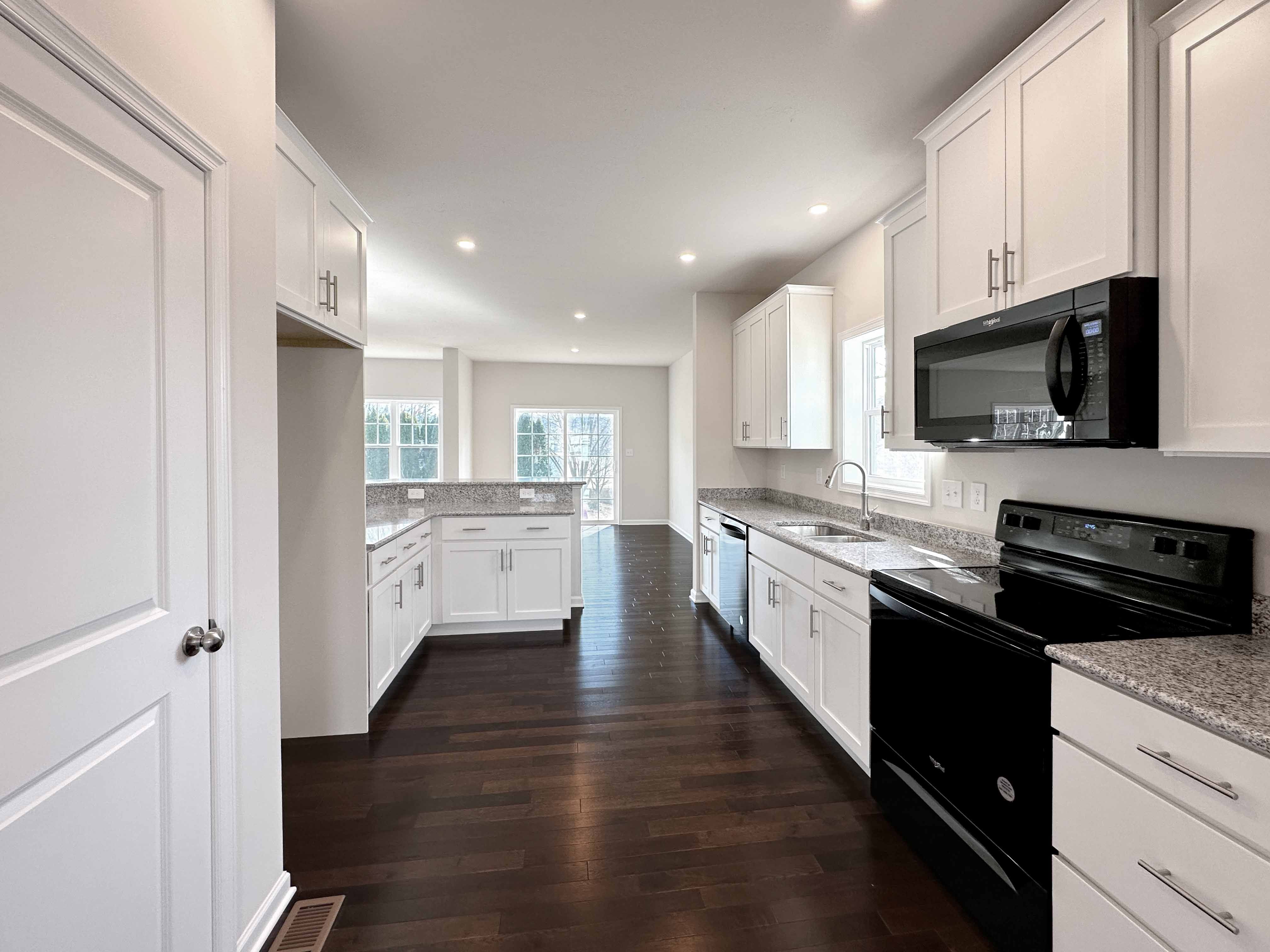 Kitchen with white cabinetry, granite countertops and black appliances.
