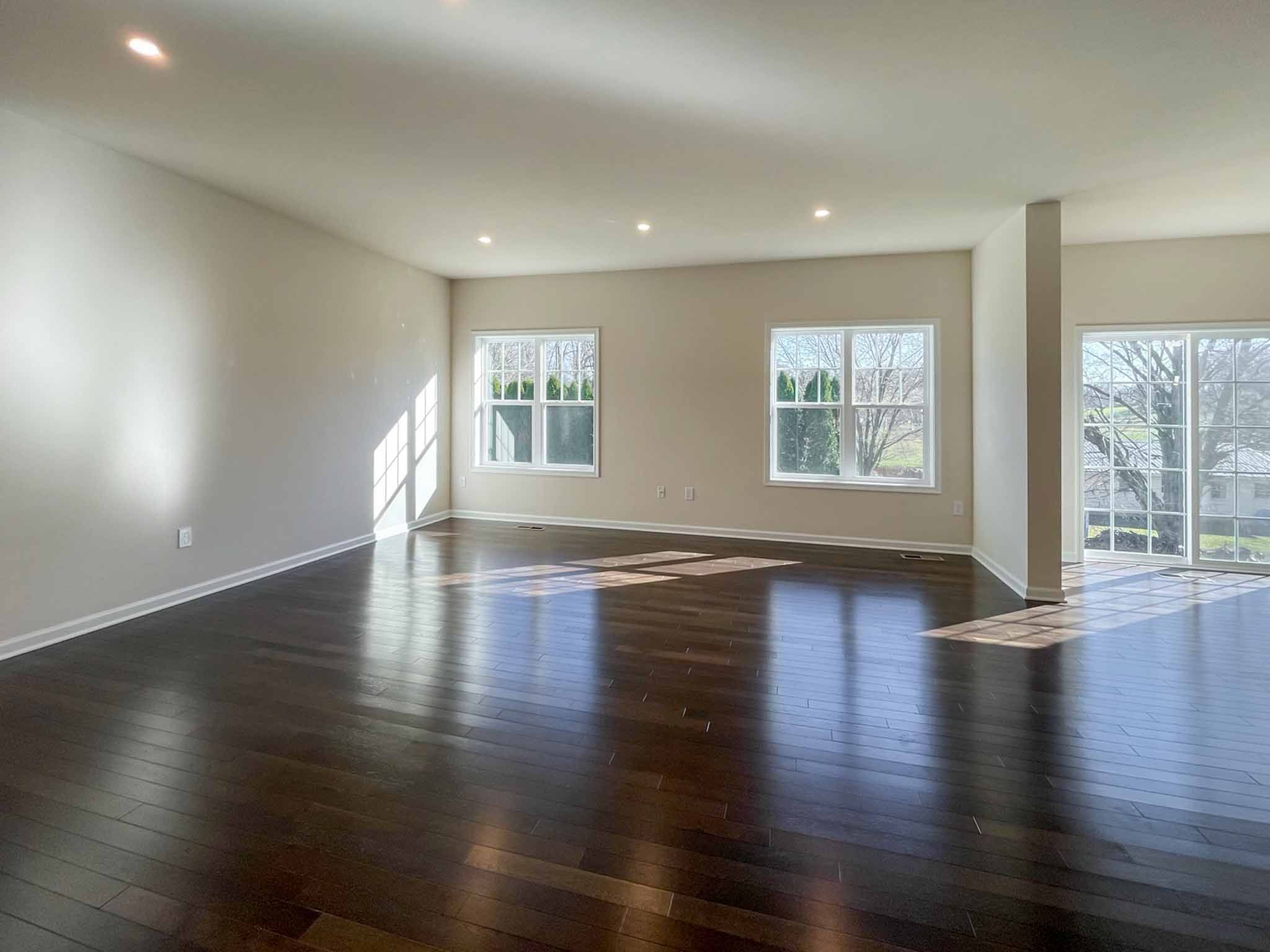 Family room with hardwood flooring and two sets of double windows on rear wall