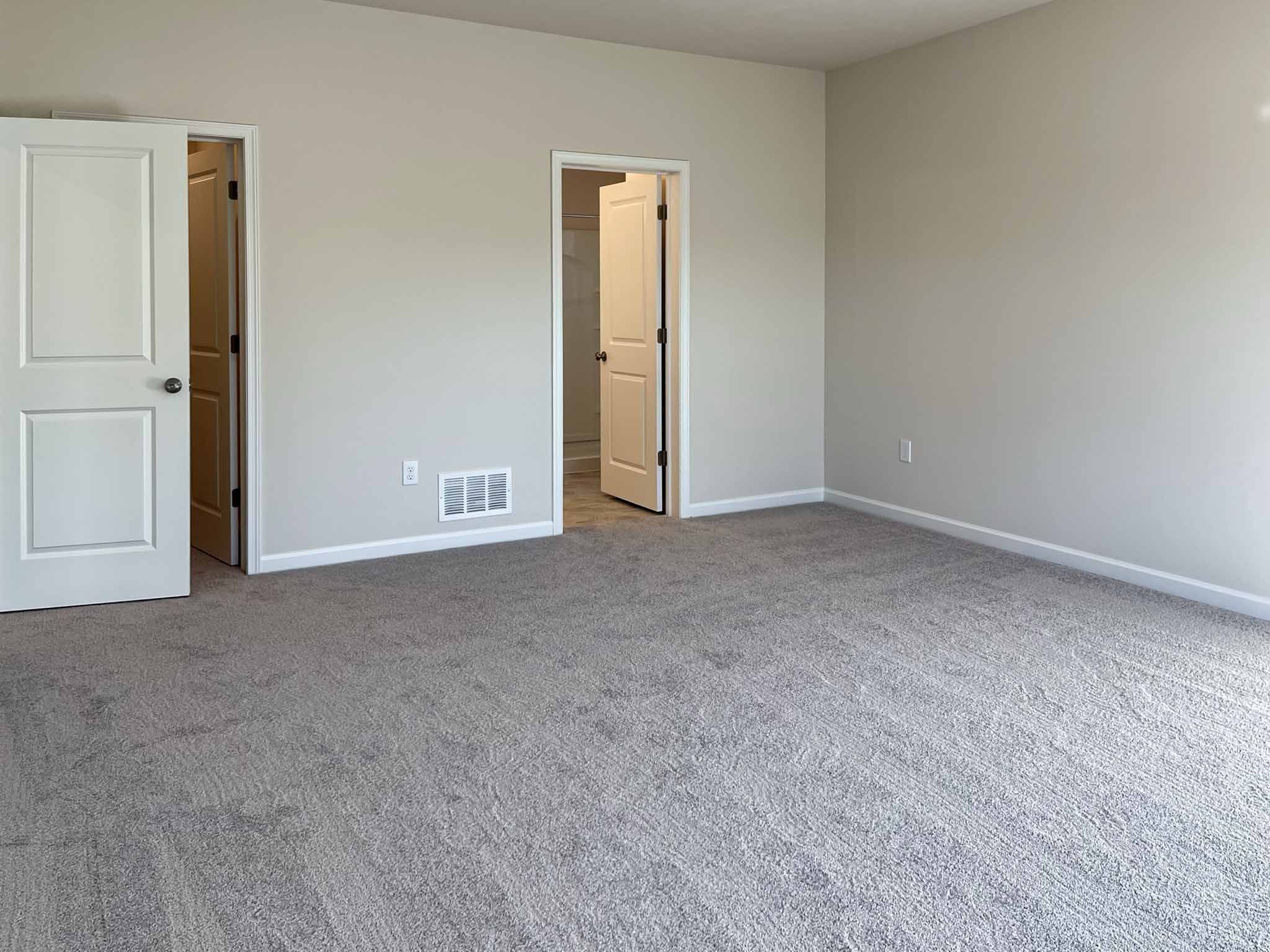 Bedroom facing doorways to bathroom and closet