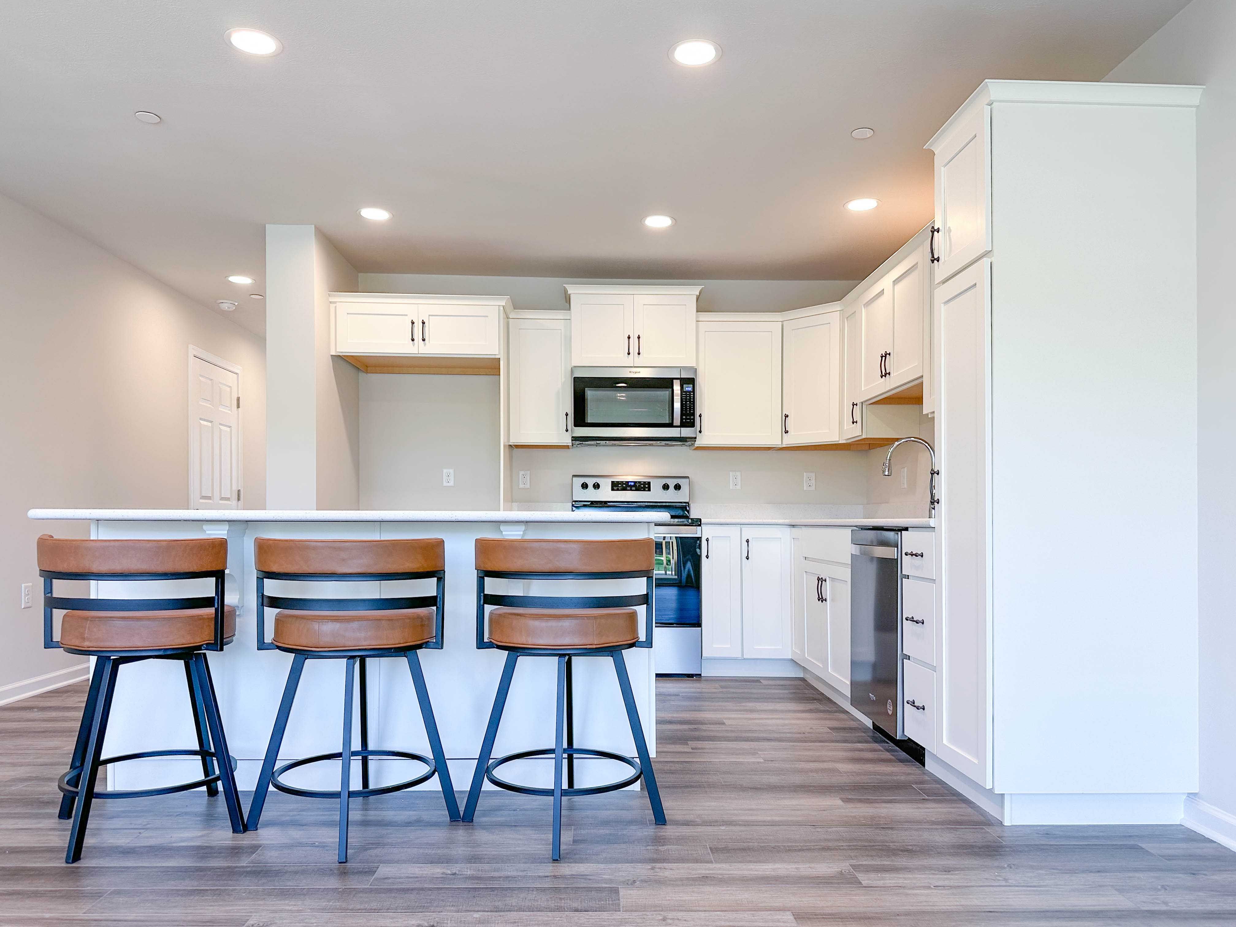 Kitchen with white cabinets and center island with bar overhang