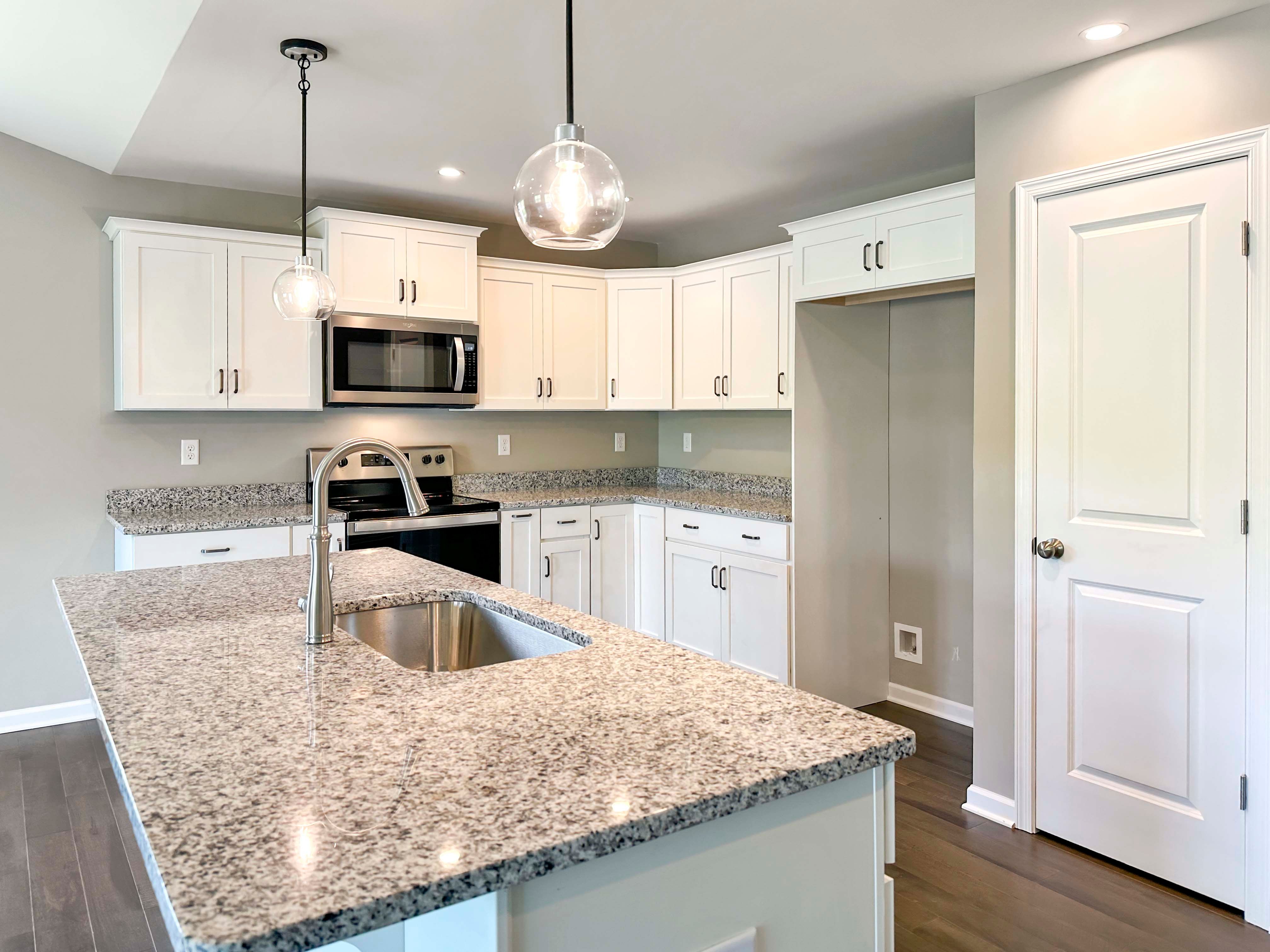 Kitchen with white cabinets,granite countertops and stainless steel appliances - pendant lights over island