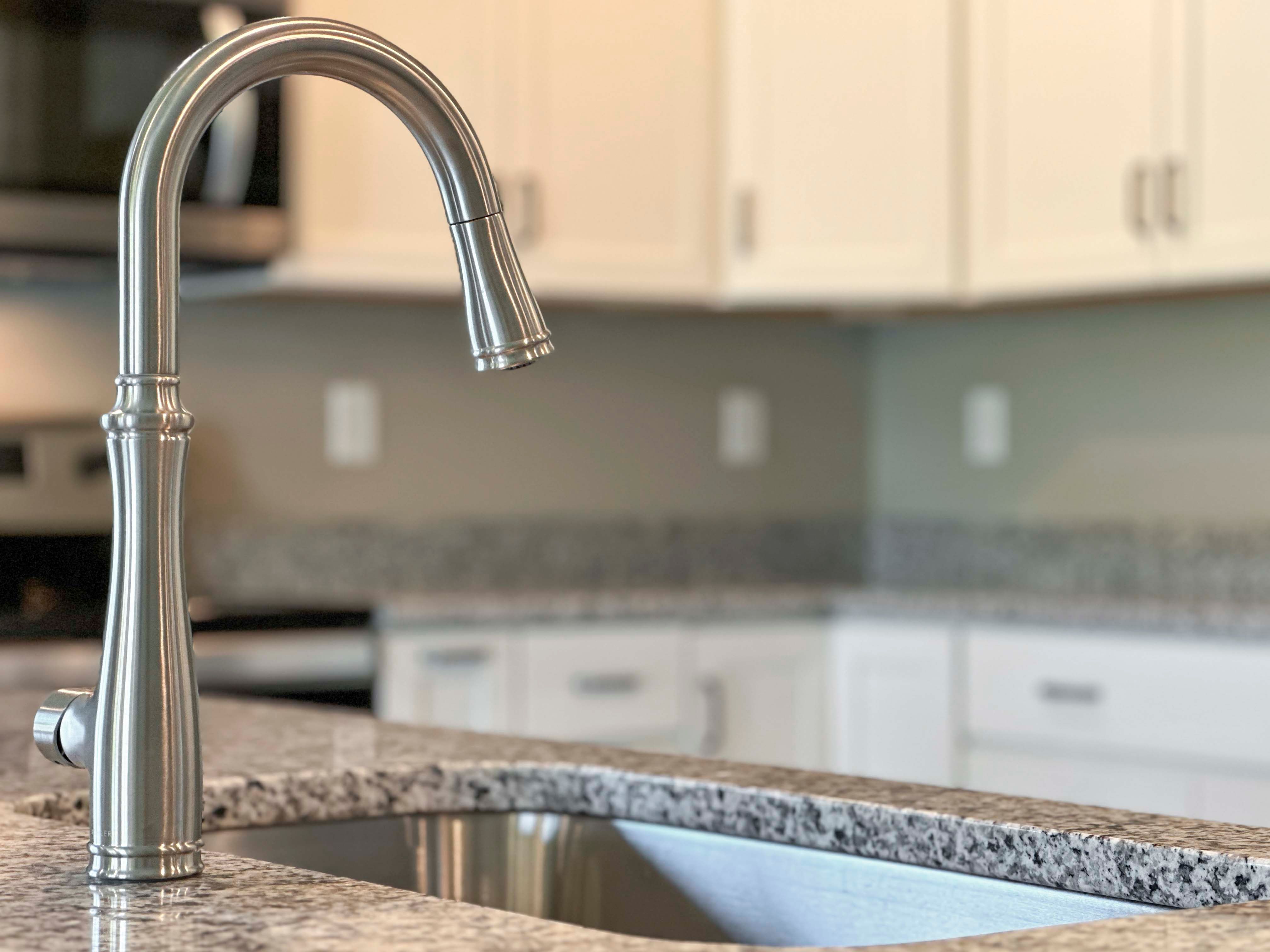 Stainless steel faucet over sink with granite countertops