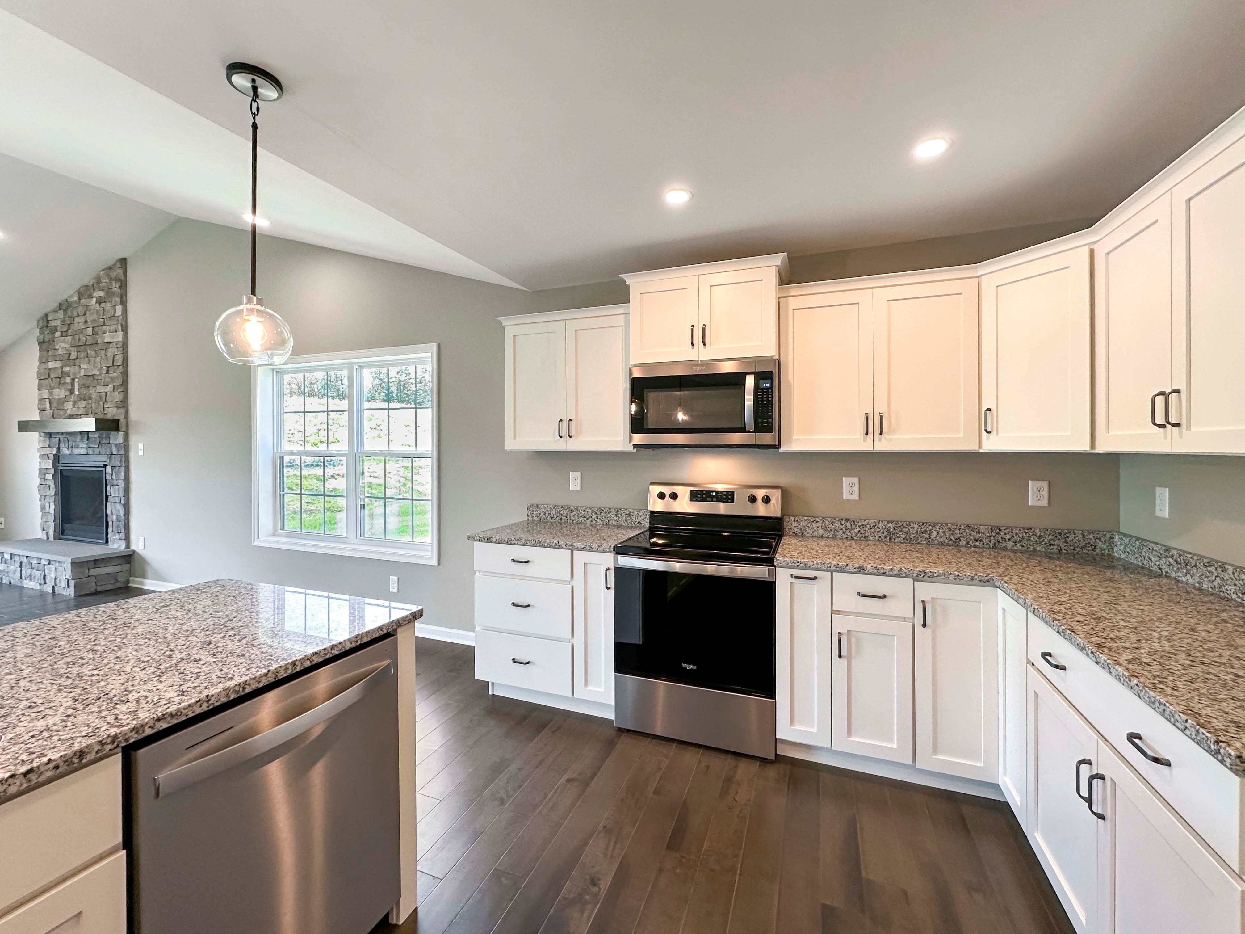 Kitchen with white cabinets,granite countertops and stainless steel appliances - pendant lights over island