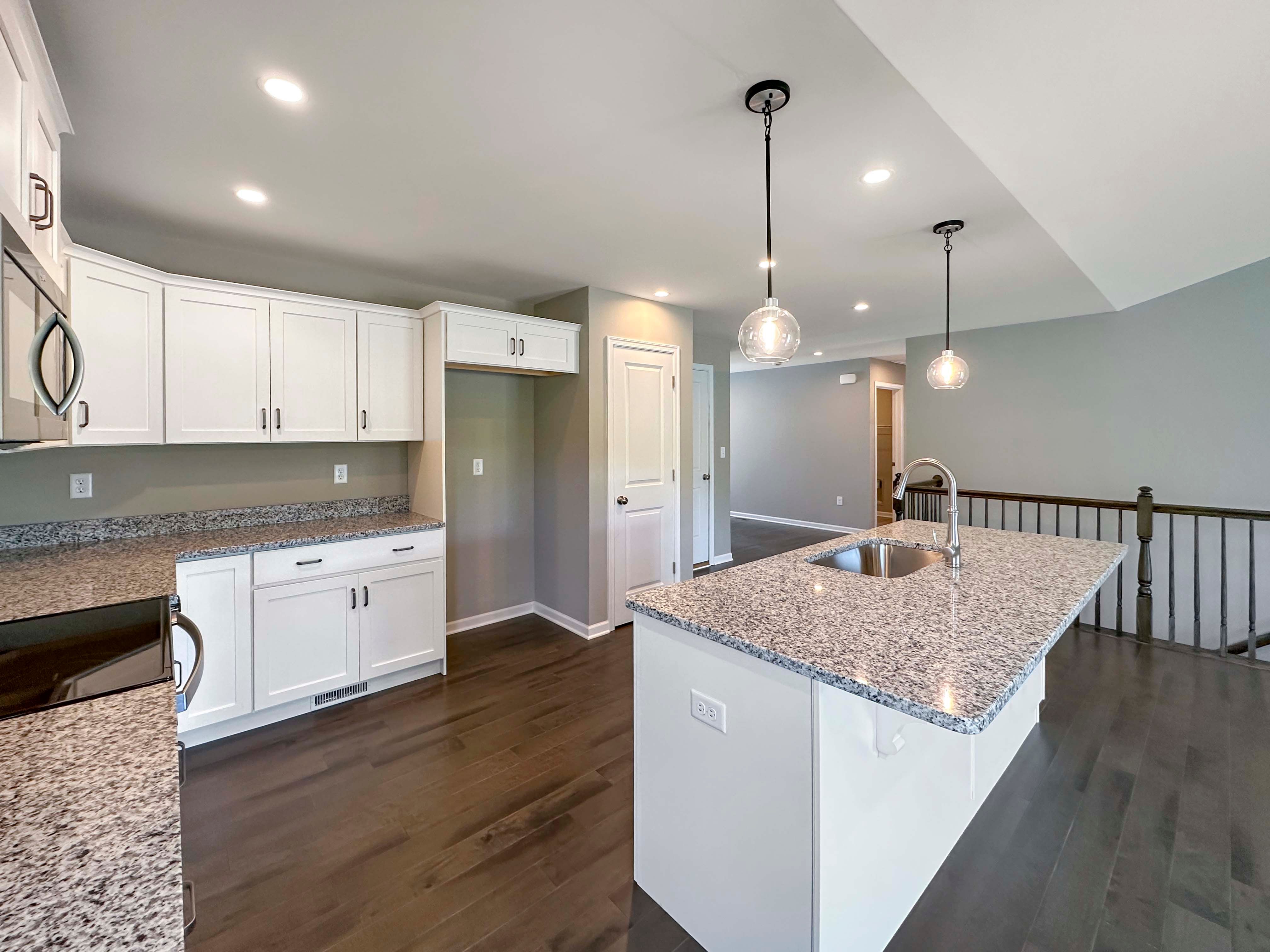 Kitchen with white cabinets,granite countertops and stainless steel appliances - pendant lights over island