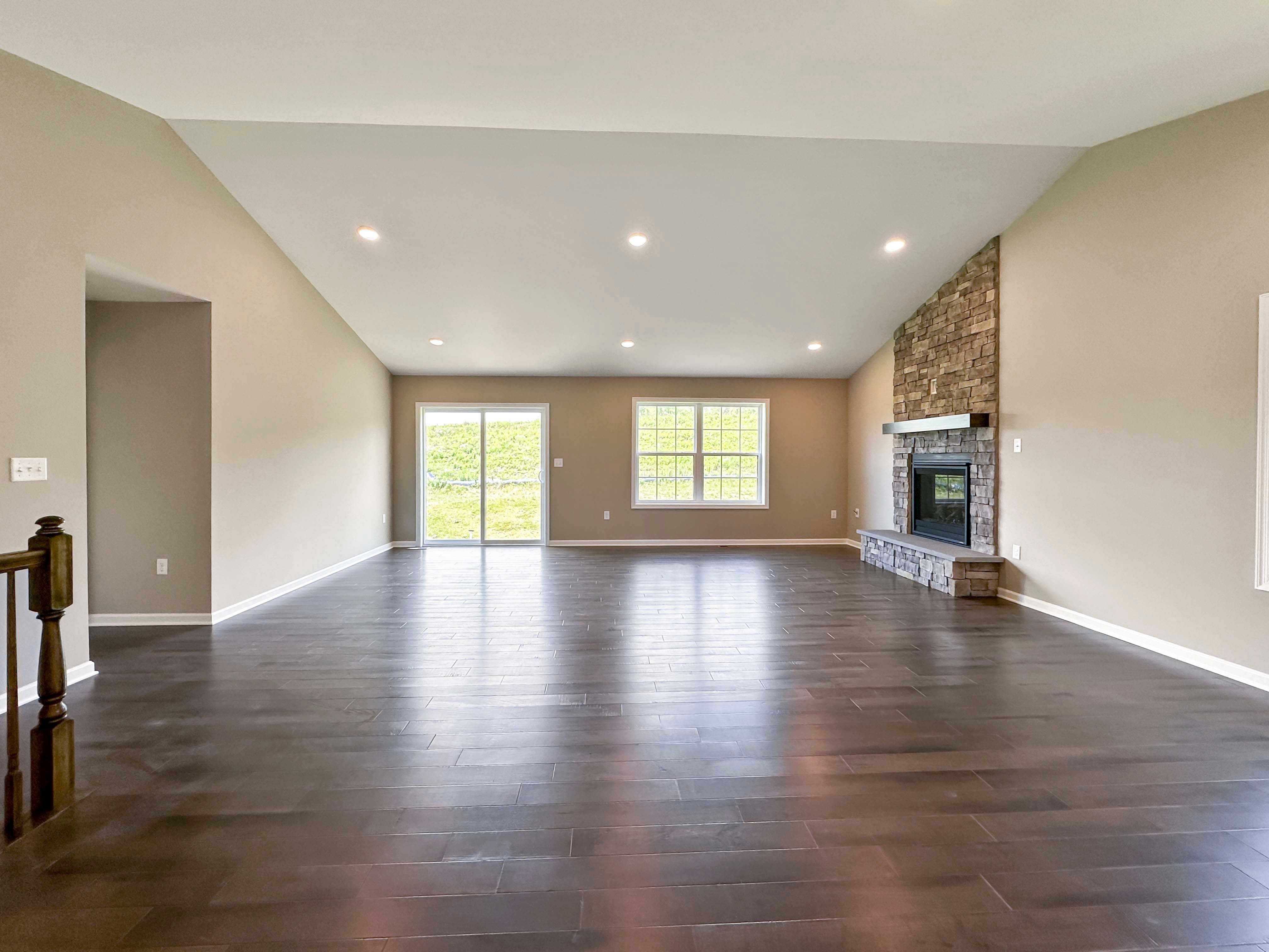 Family room with hardwood flooring and vaulted ceiling and stone fireplace