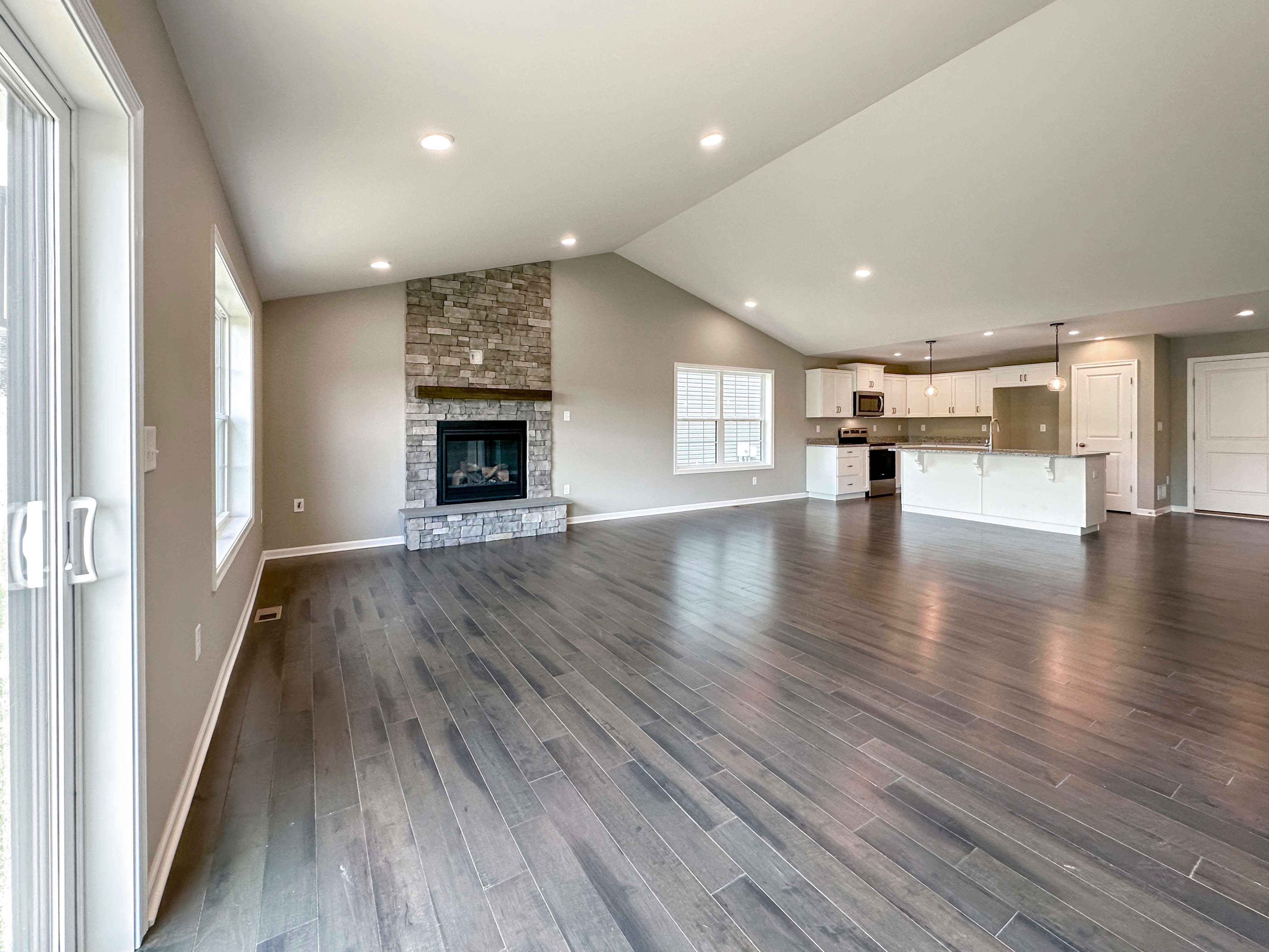 Family room with hardwood flooring and vaulted ceiling and stone fireplace