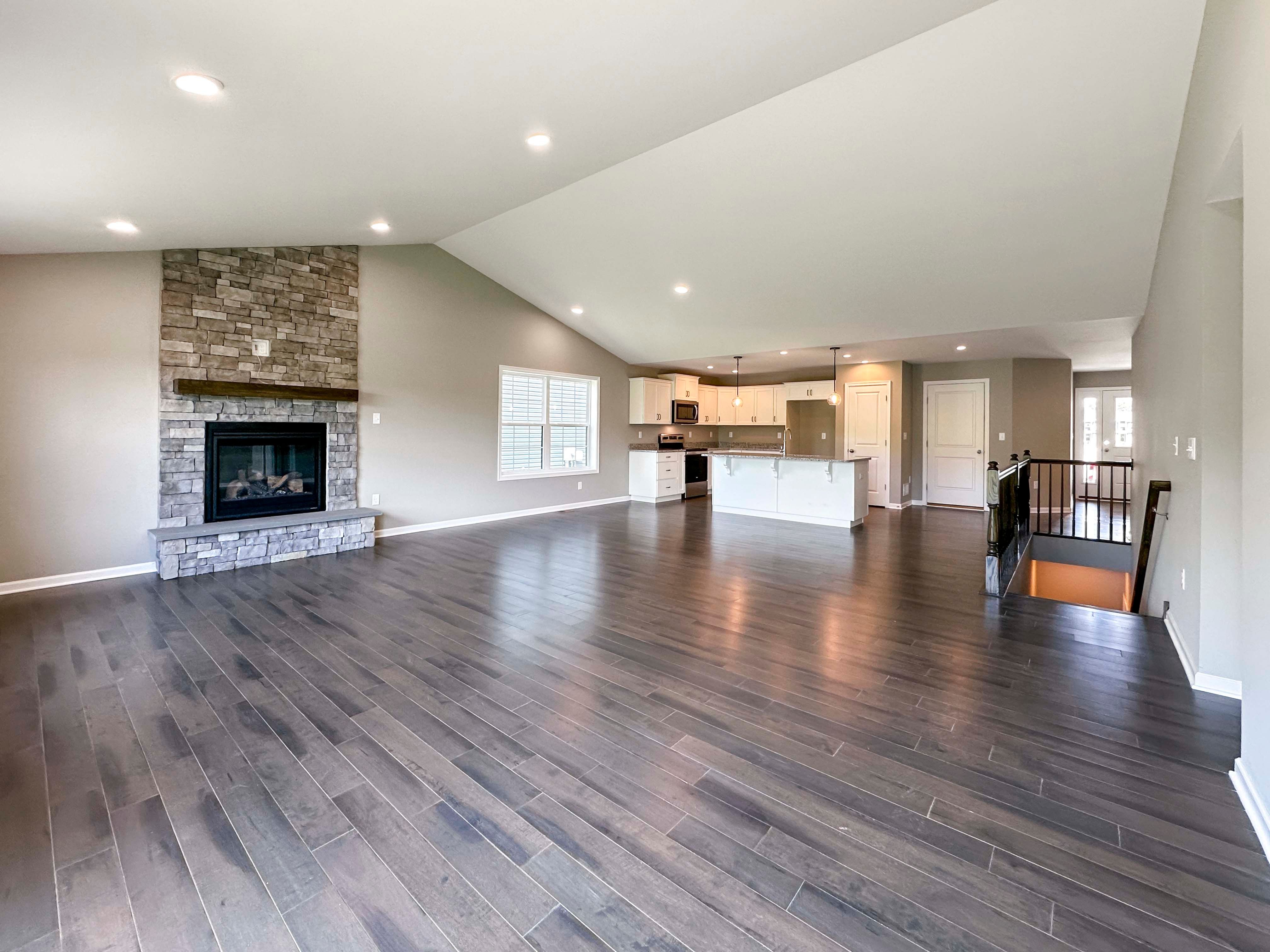 Family room with hardwood flooring and vaulted ceiling and stone fireplace