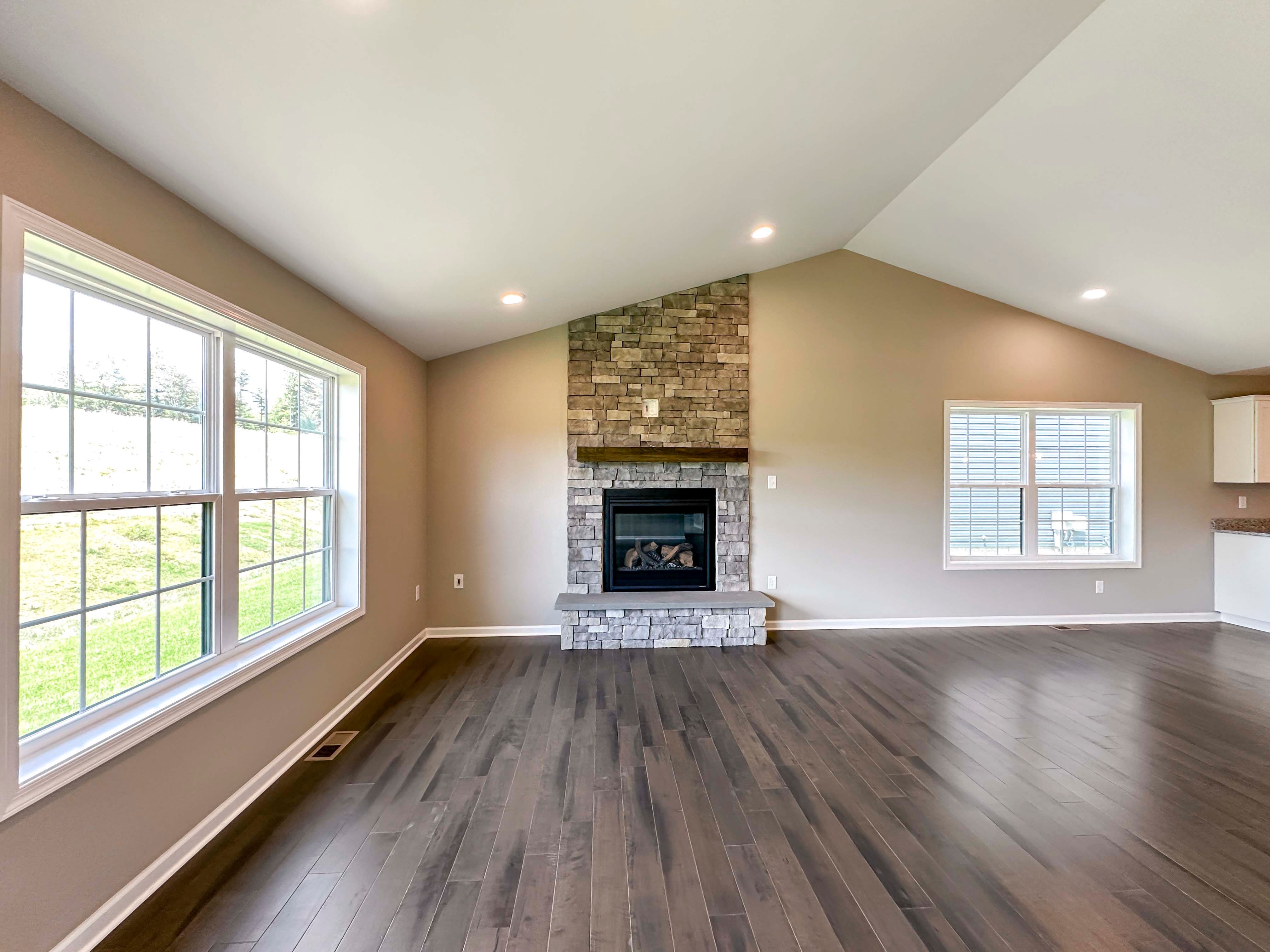 Family room with hardwood flooring and vaulted ceiling and stone fireplace
