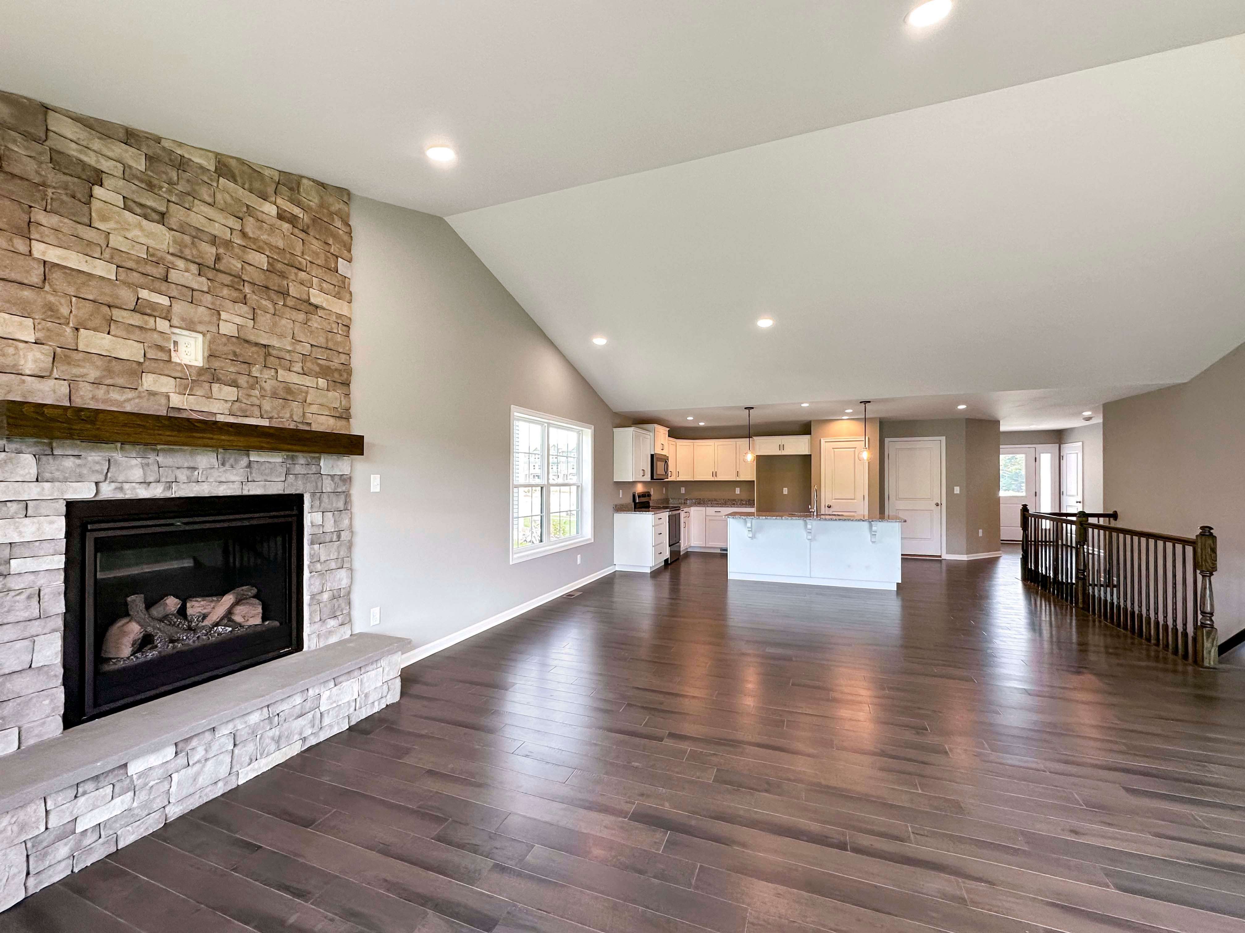 Family room with hardwood flooring and vaulted ceiling and stone fireplace