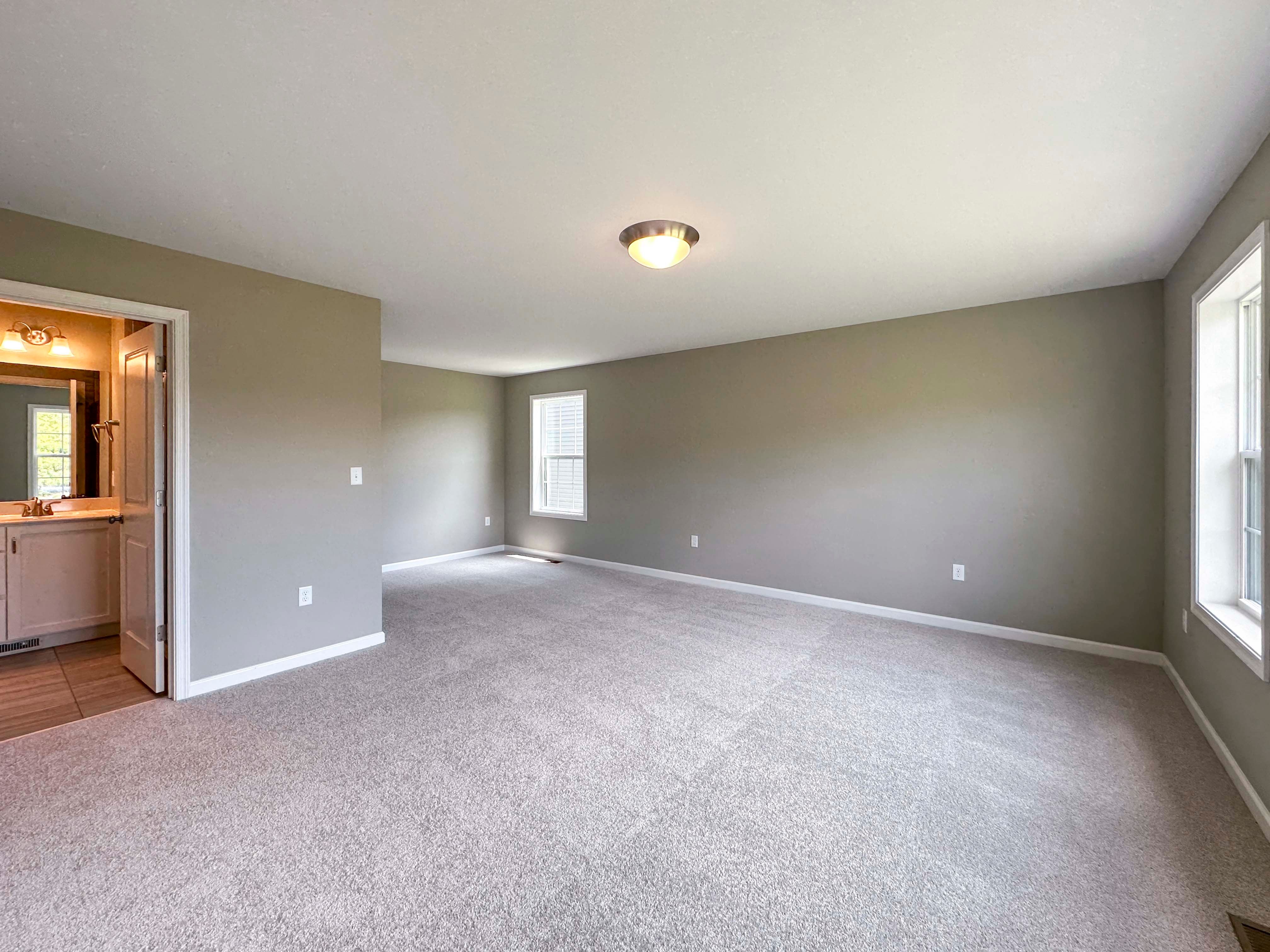 Unfurnished bedroom with carpet flooring and triple windows on rear wall
