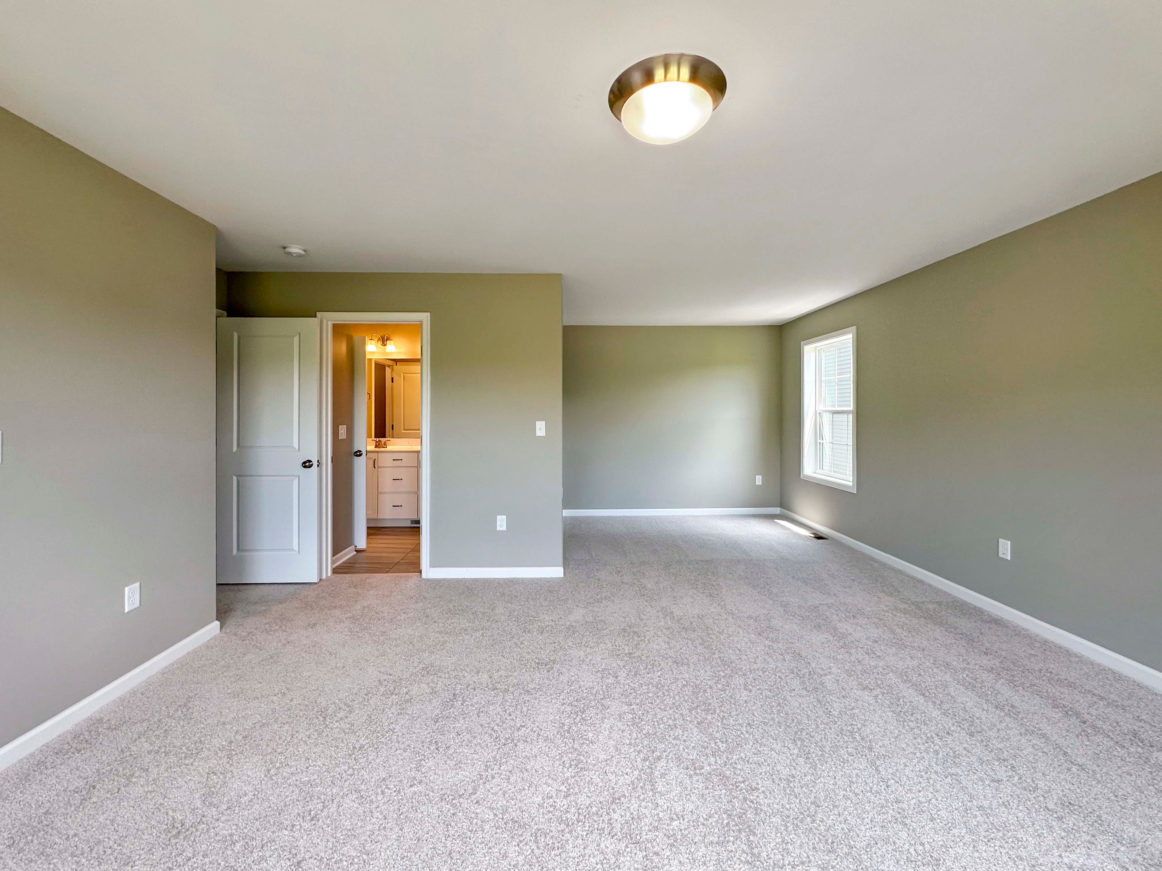 Unfurnished bedroom with carpet flooring and triple windows on rear wall
