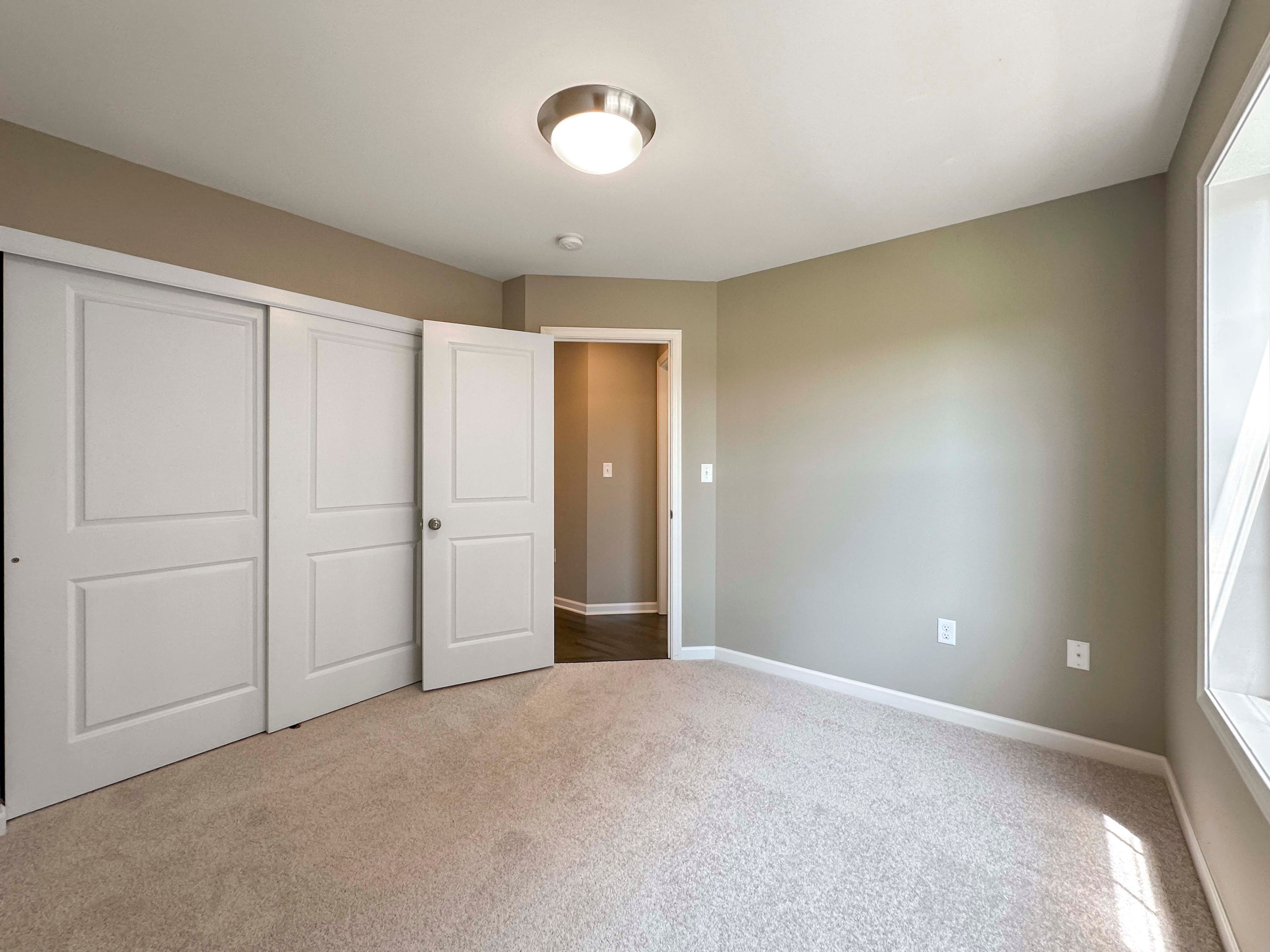 Unfurnished bedroom with carpet flooring - facing doors to closet and hall