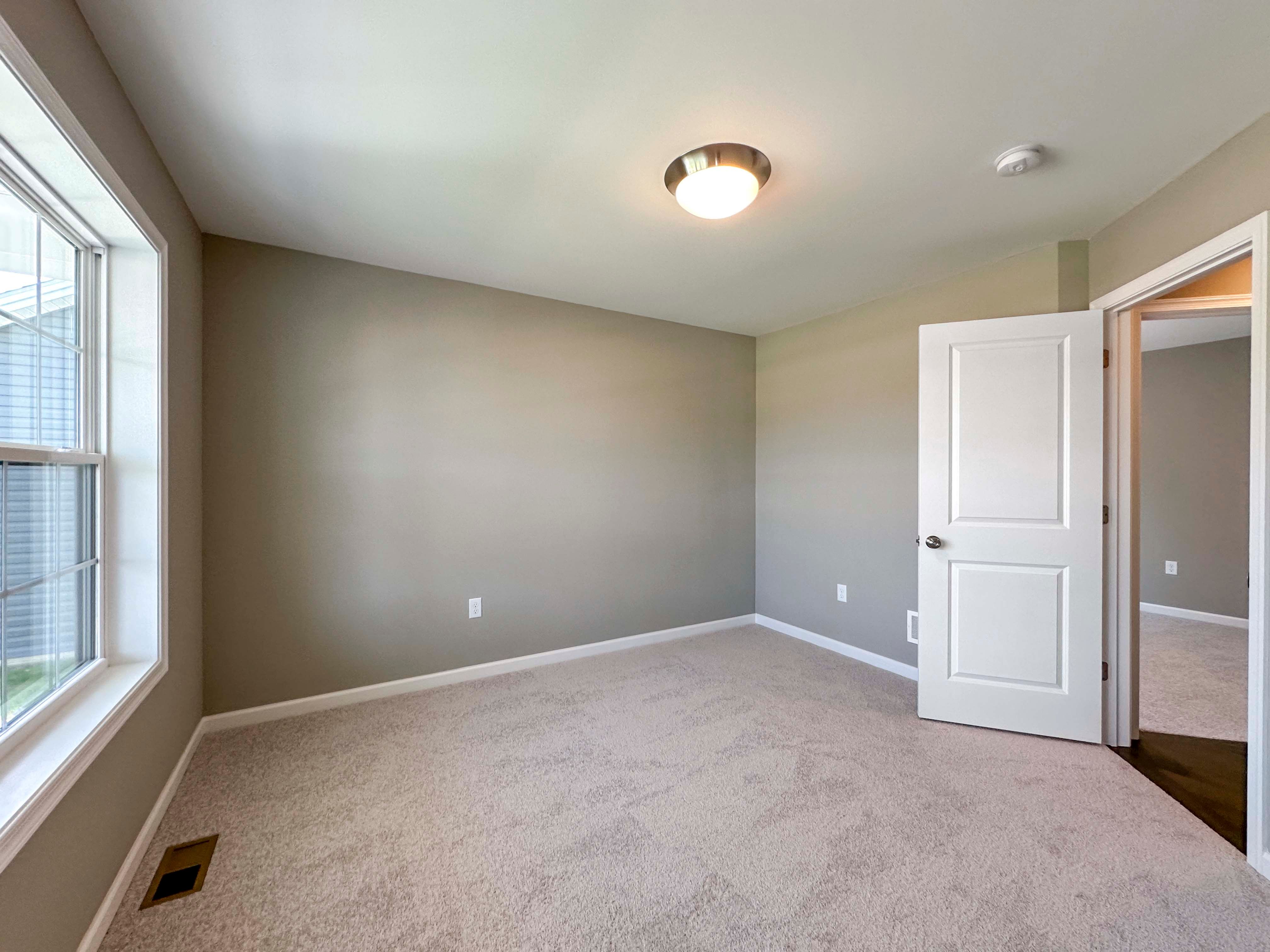 Unfurnished bedroom with carpet flooring and dual windows