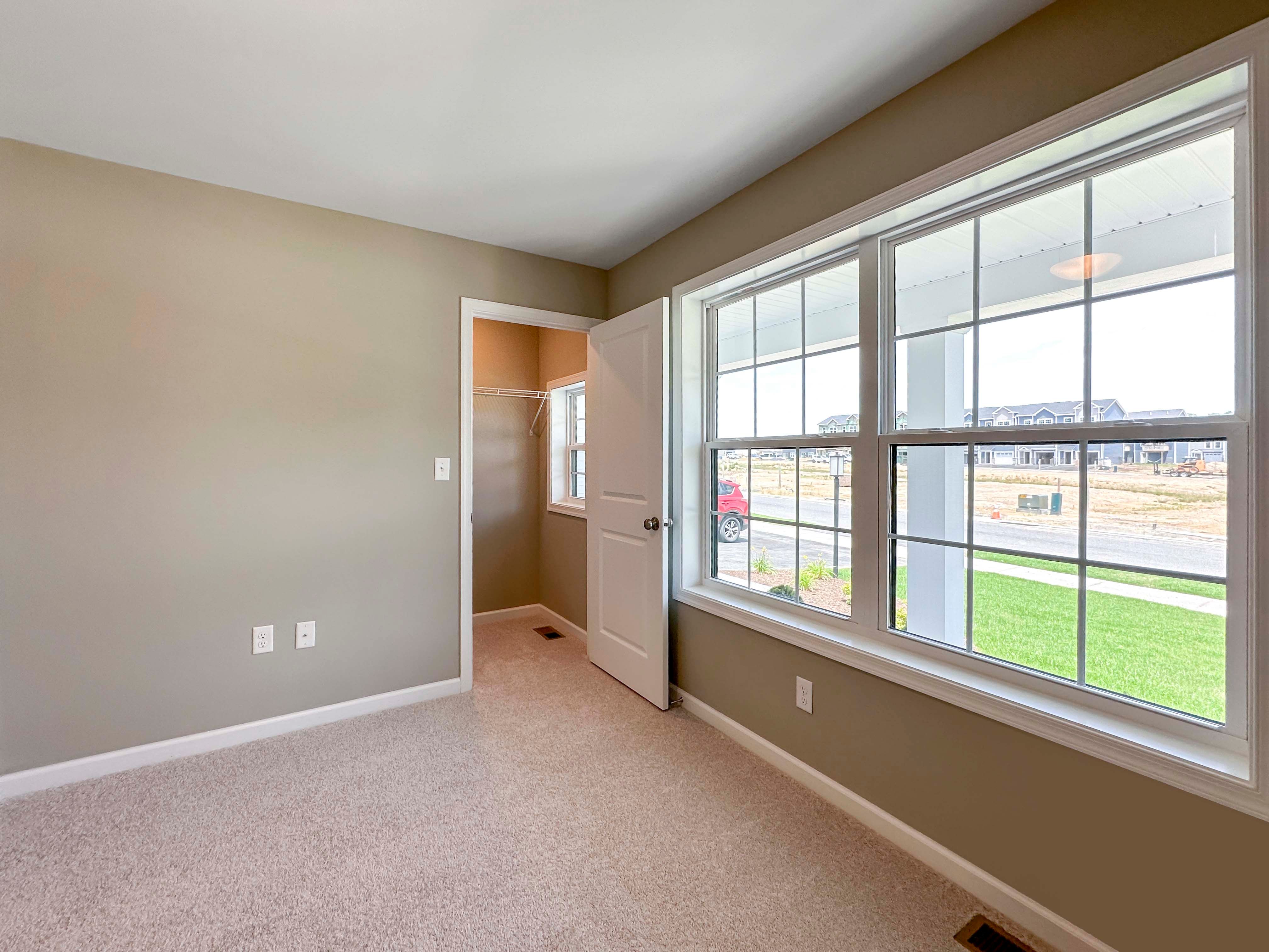 Unfurnished bedroom with carpet flooring and dual windows - facing doorway to closet