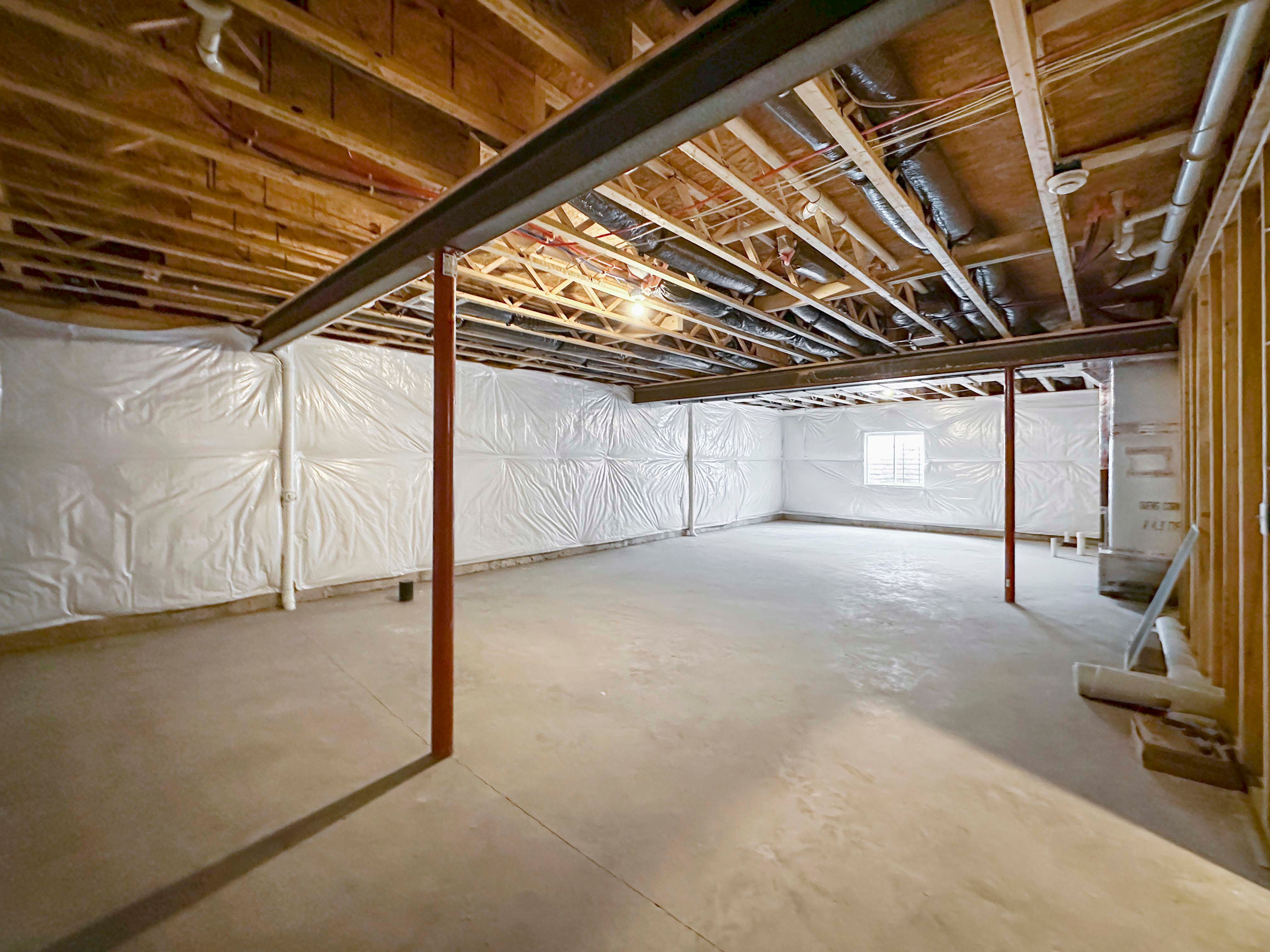 Unfinished basement with egress window well on rear wall