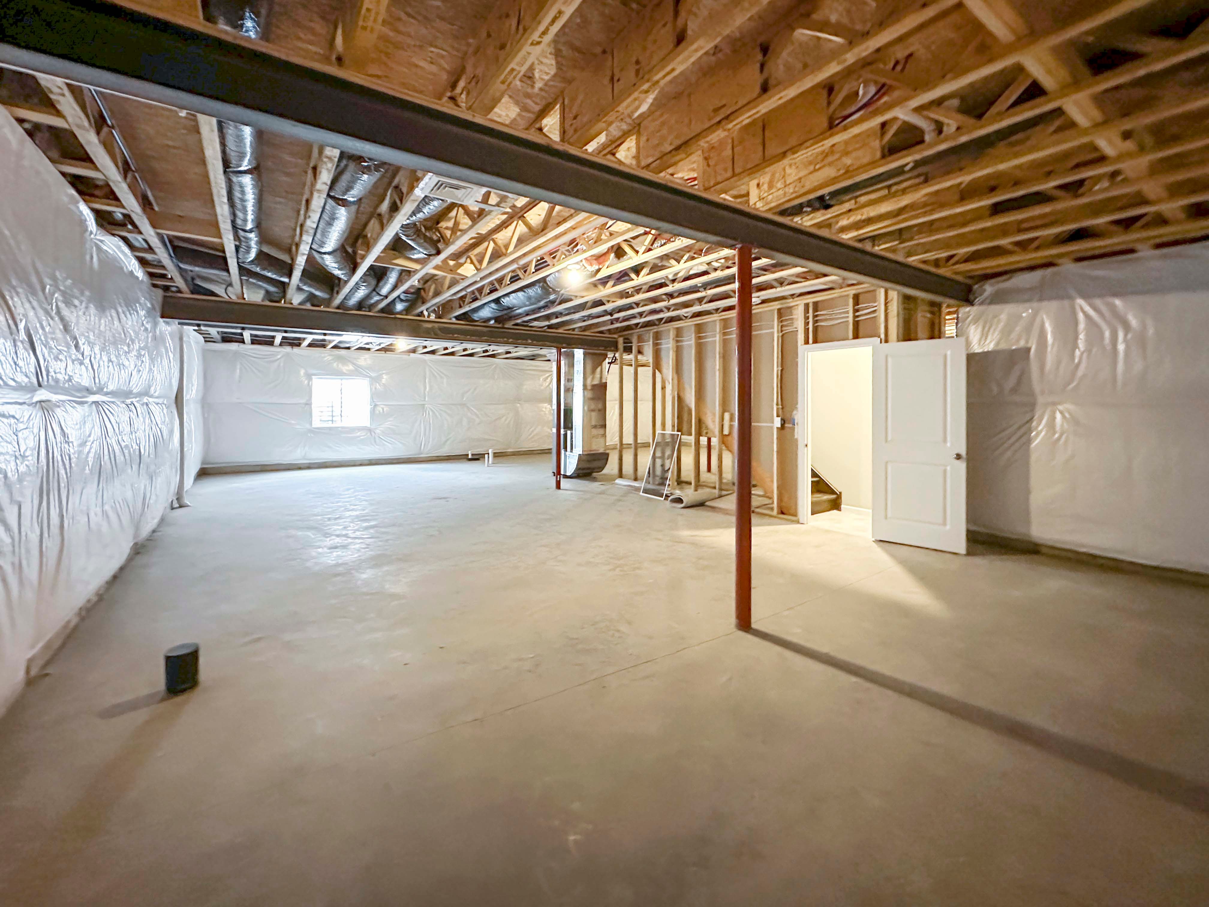 Unfinished basement with egress window well on rear wall