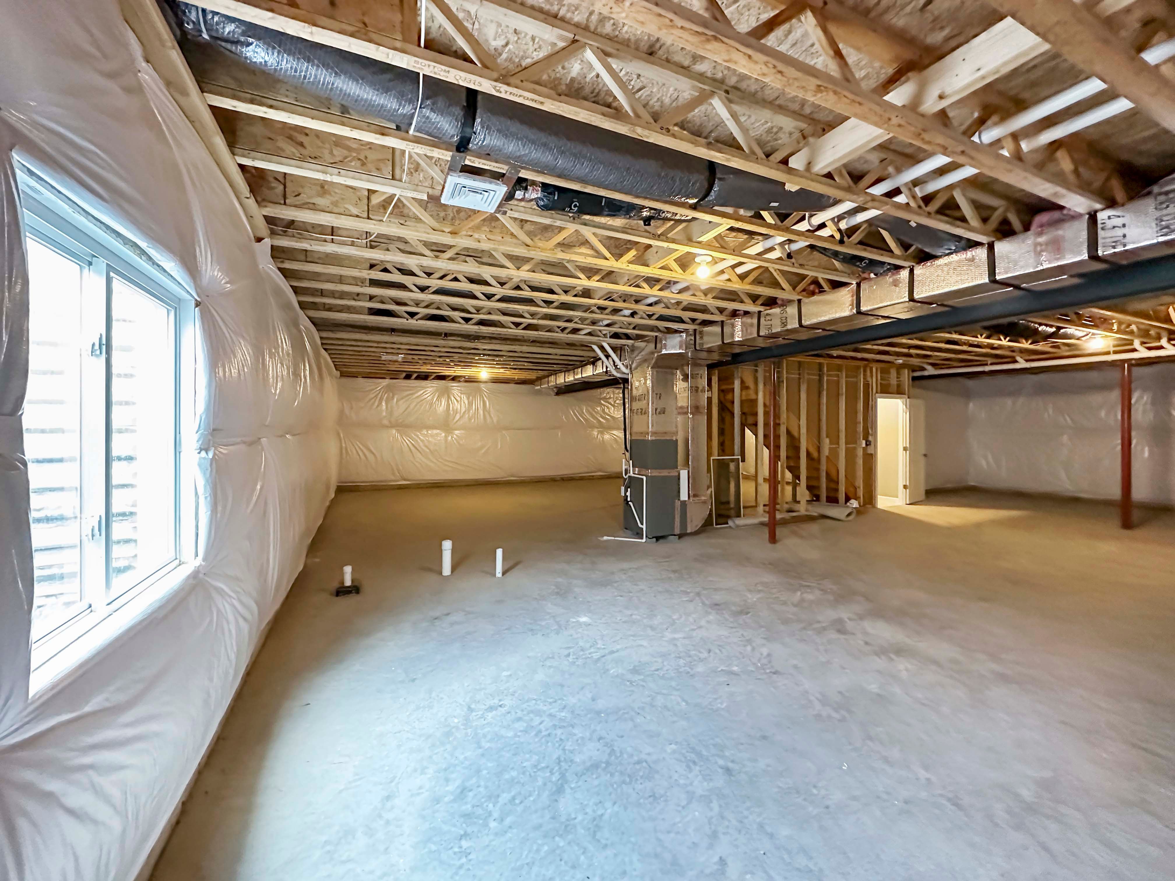 Unfinished basement with egress window well on rear wall