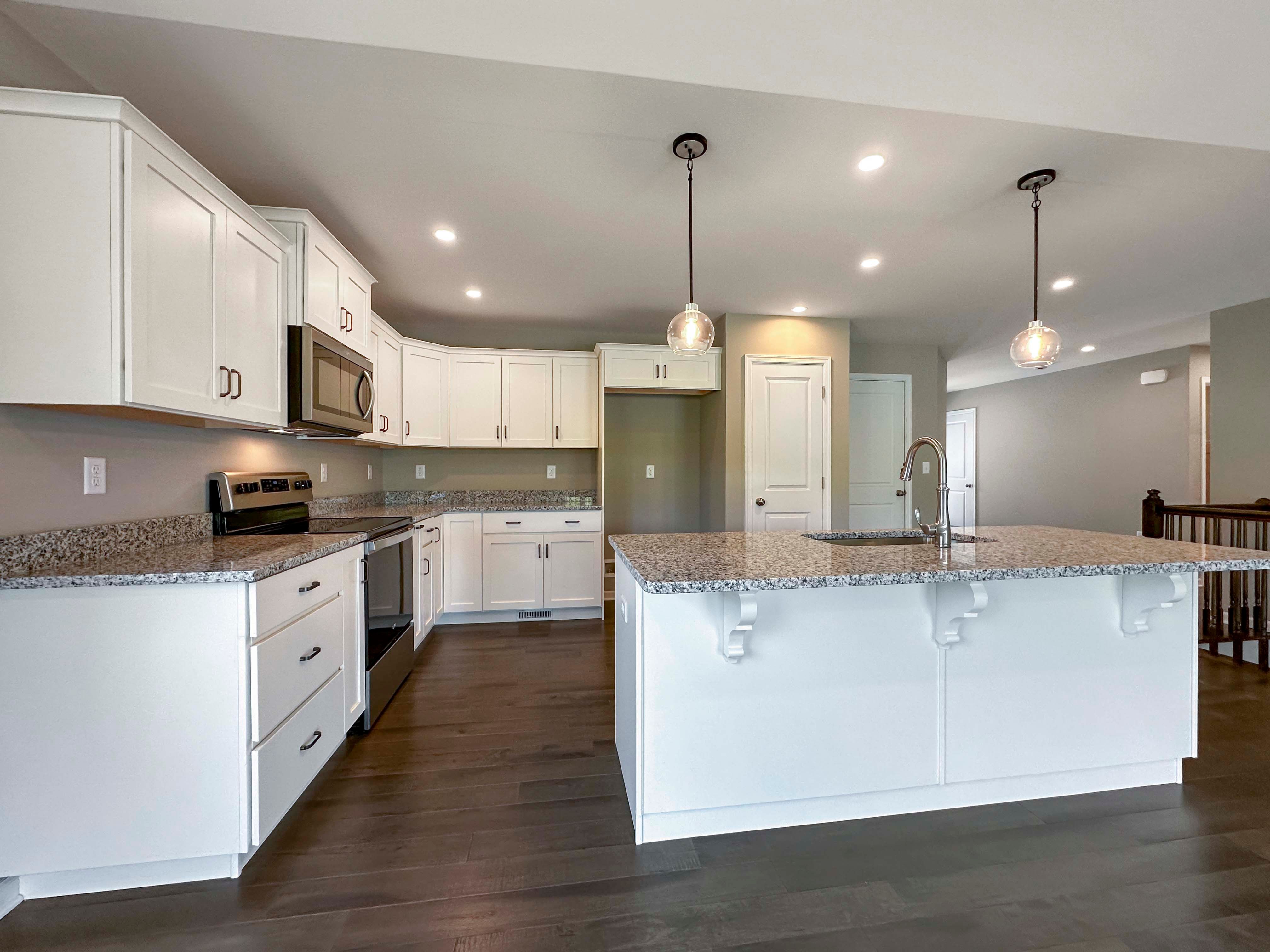 Kitchen with white cabinets,granite countertops and stainless steel appliances - pendant lights over island
