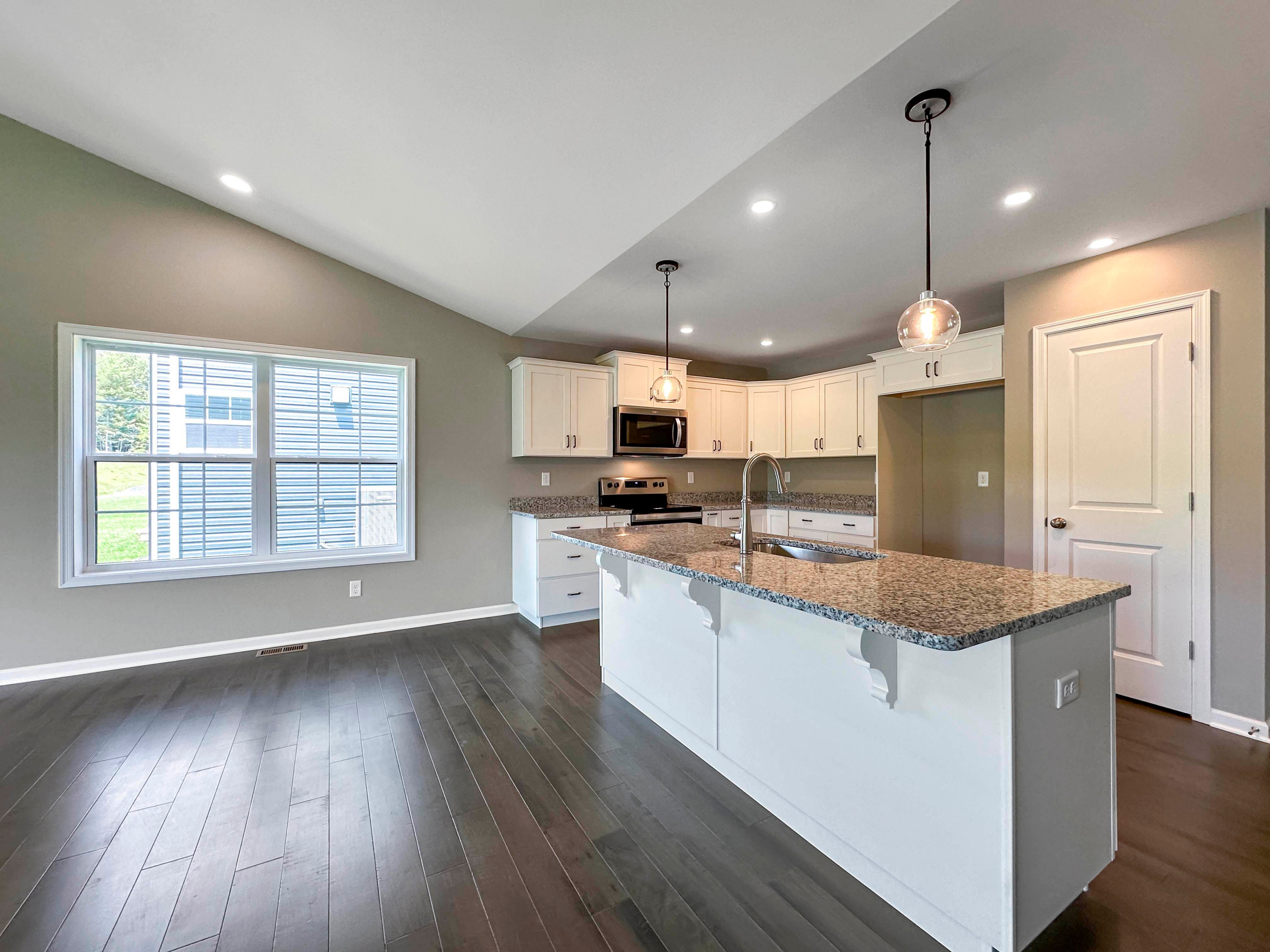 Kitchen with white cabinets,granite countertops and stainless steel appliances - pendant lights over island