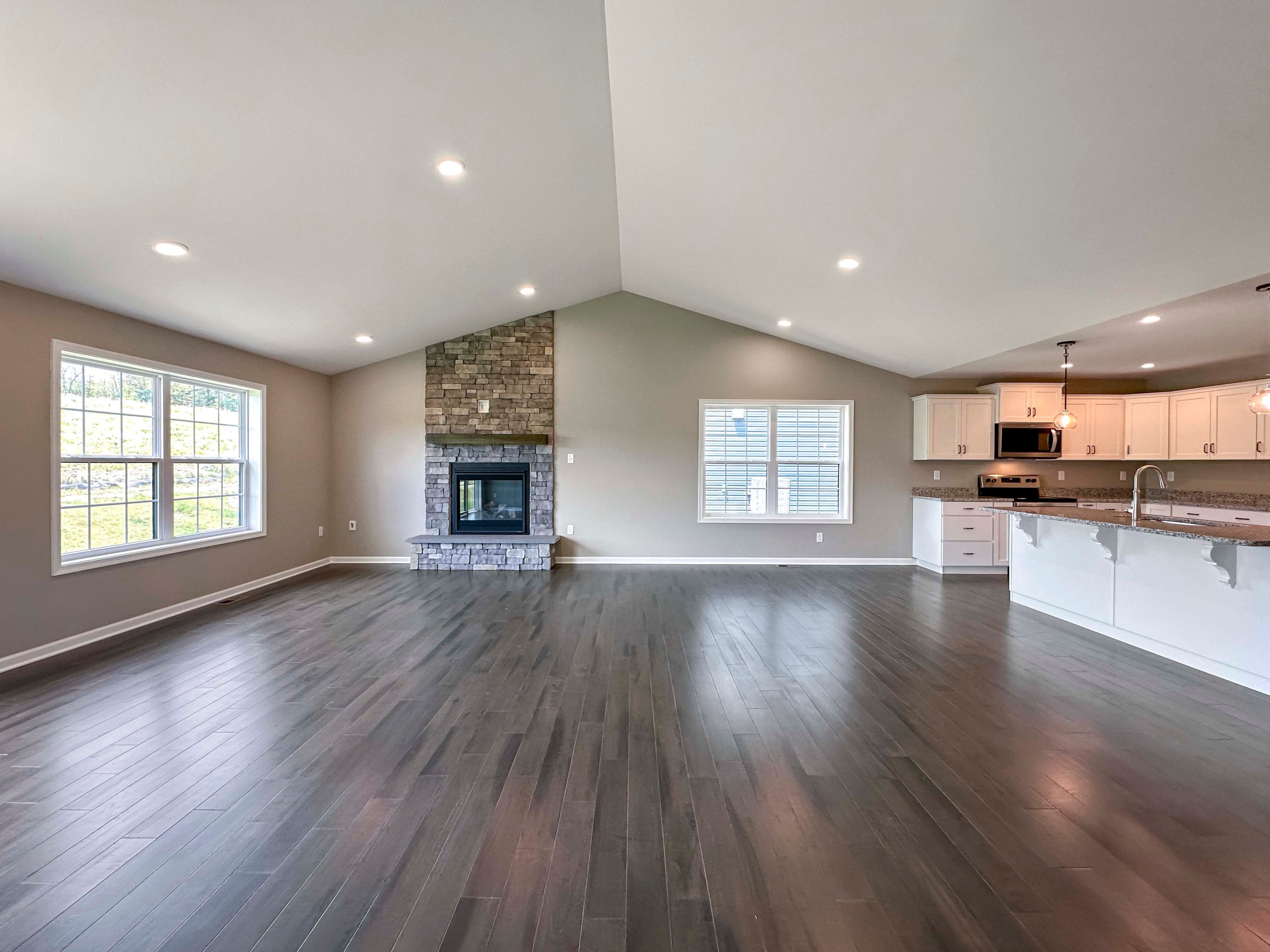 Family room with hardwood flooring and vaulted ceiling and stone fireplace