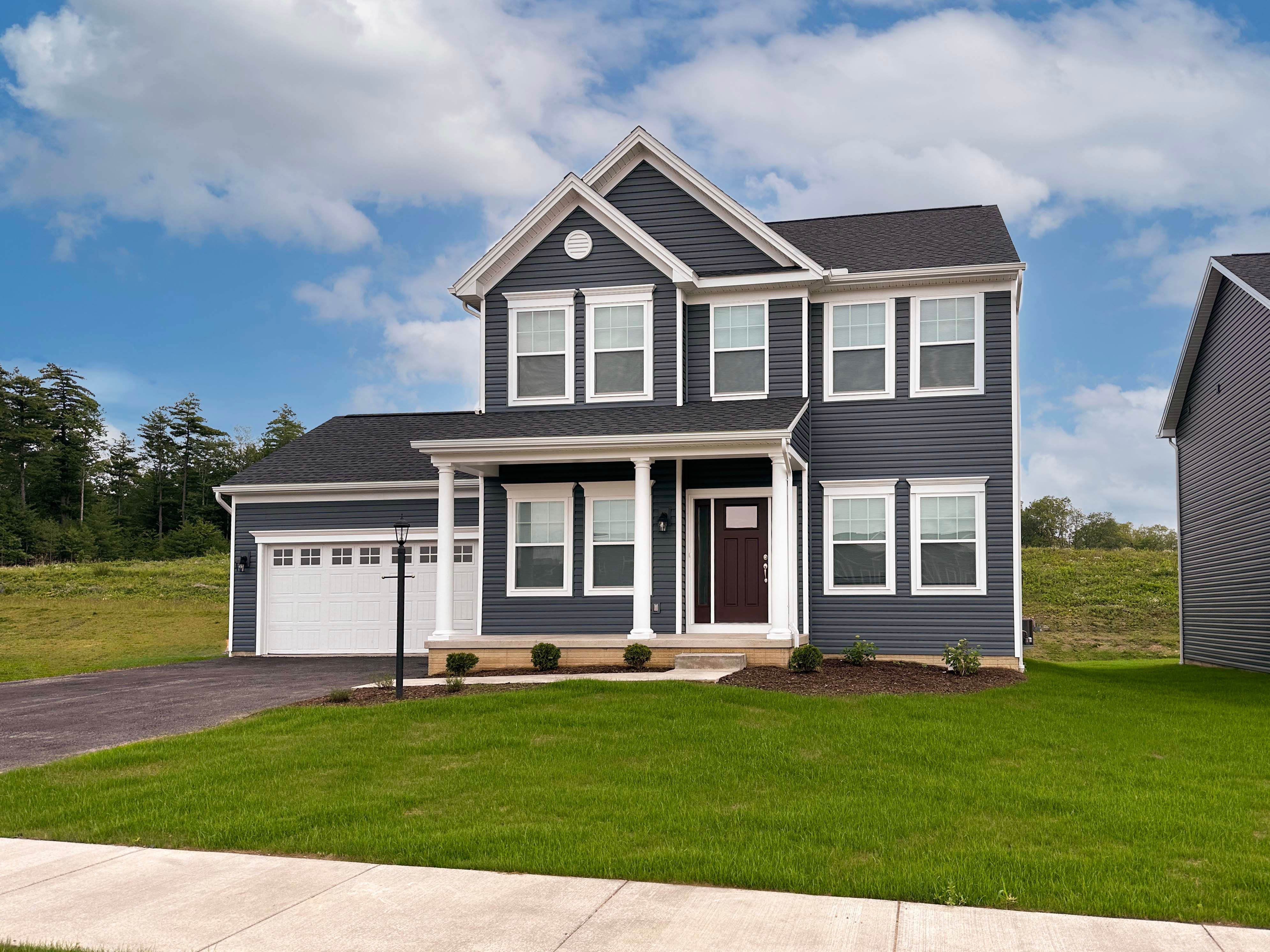 Front exterior view of the Fairmont floorplan by S&A Homes - two story home with covered front porch, double gable on roof, and two car attached garage