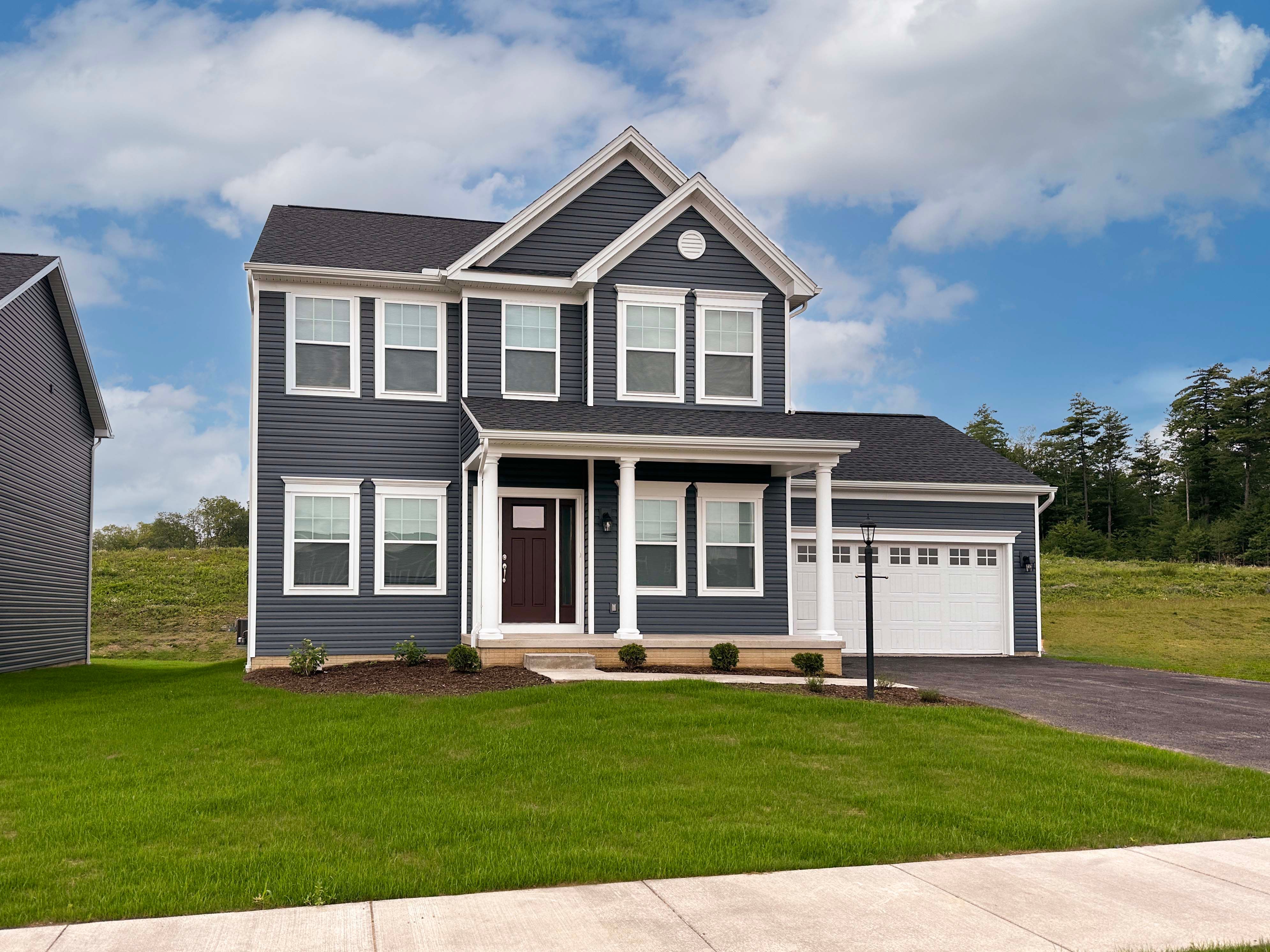 Fairmont- Front exterior - 2 story home with front porch, 2 car front entry attached garage, and vinyl siding.