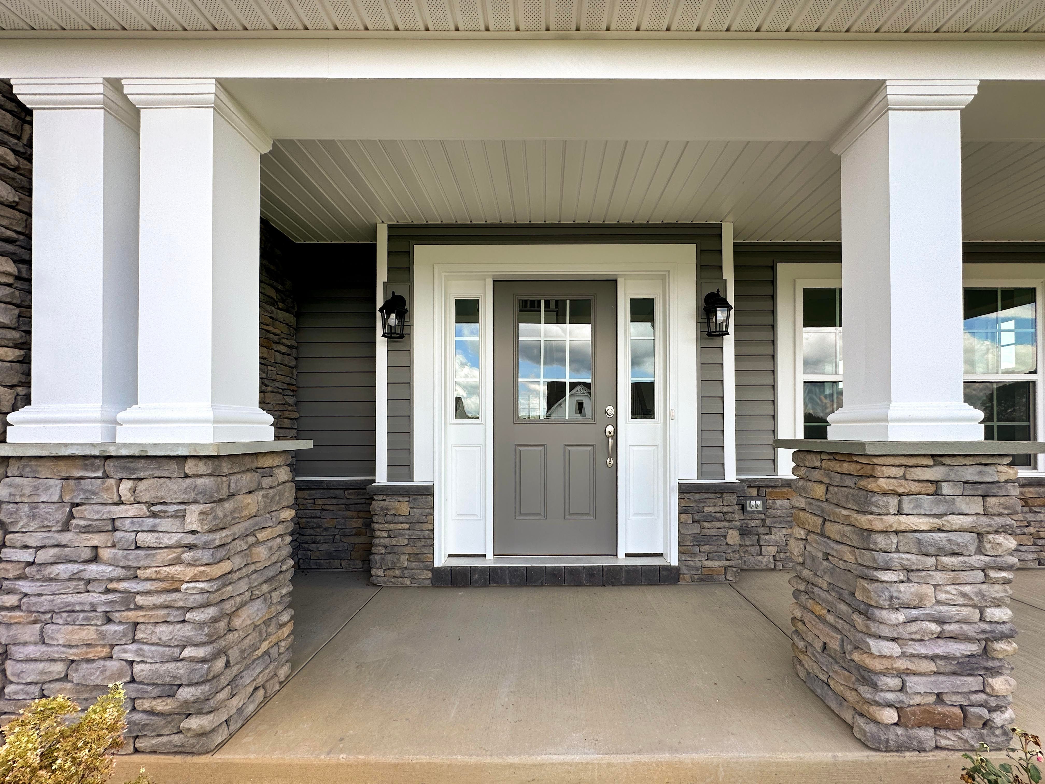 Front porch with white columns on both sides, accent stone halfway up - facing the front door.