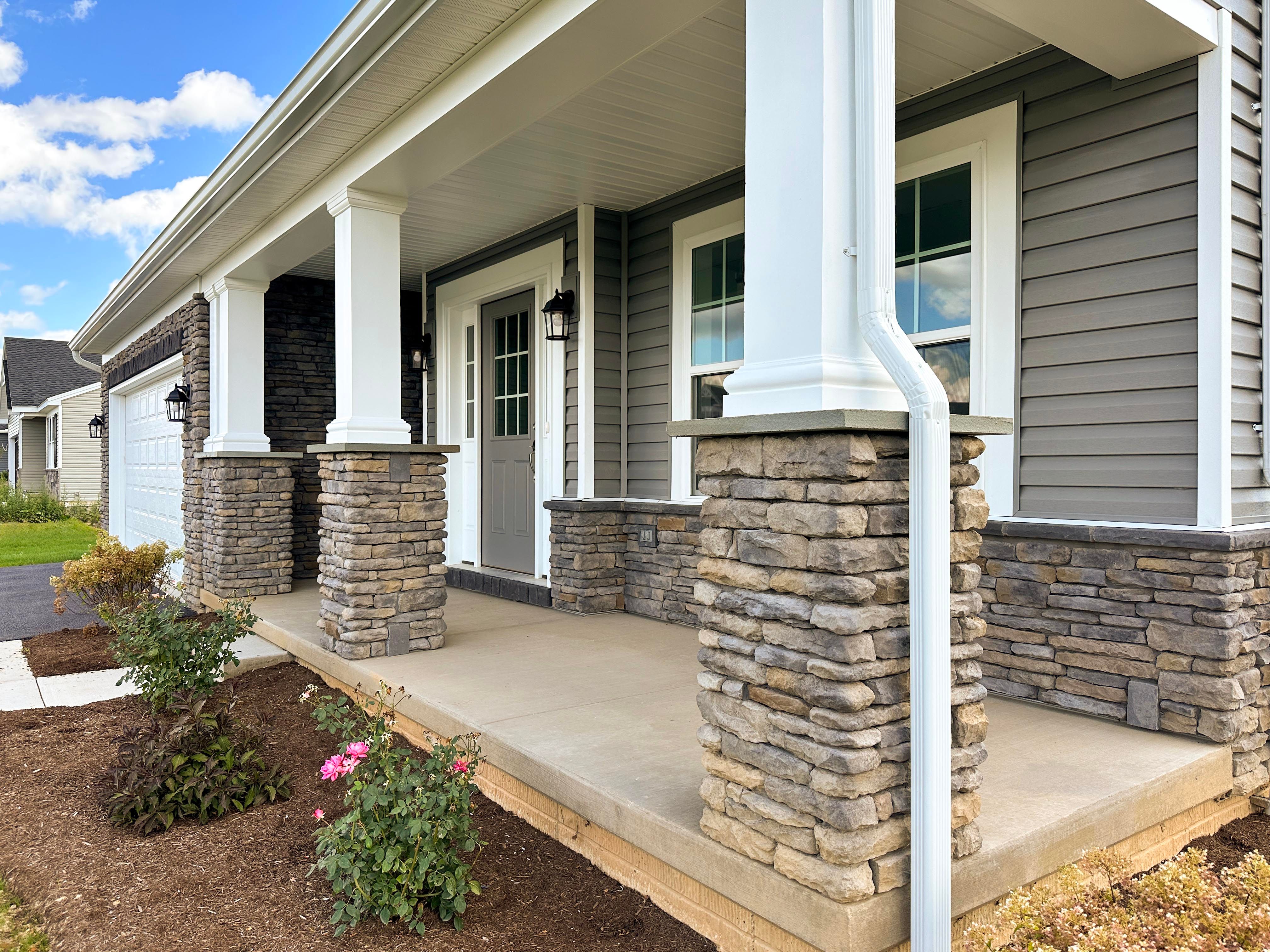 Front porch with three columns, vinyl siding, stone accent.