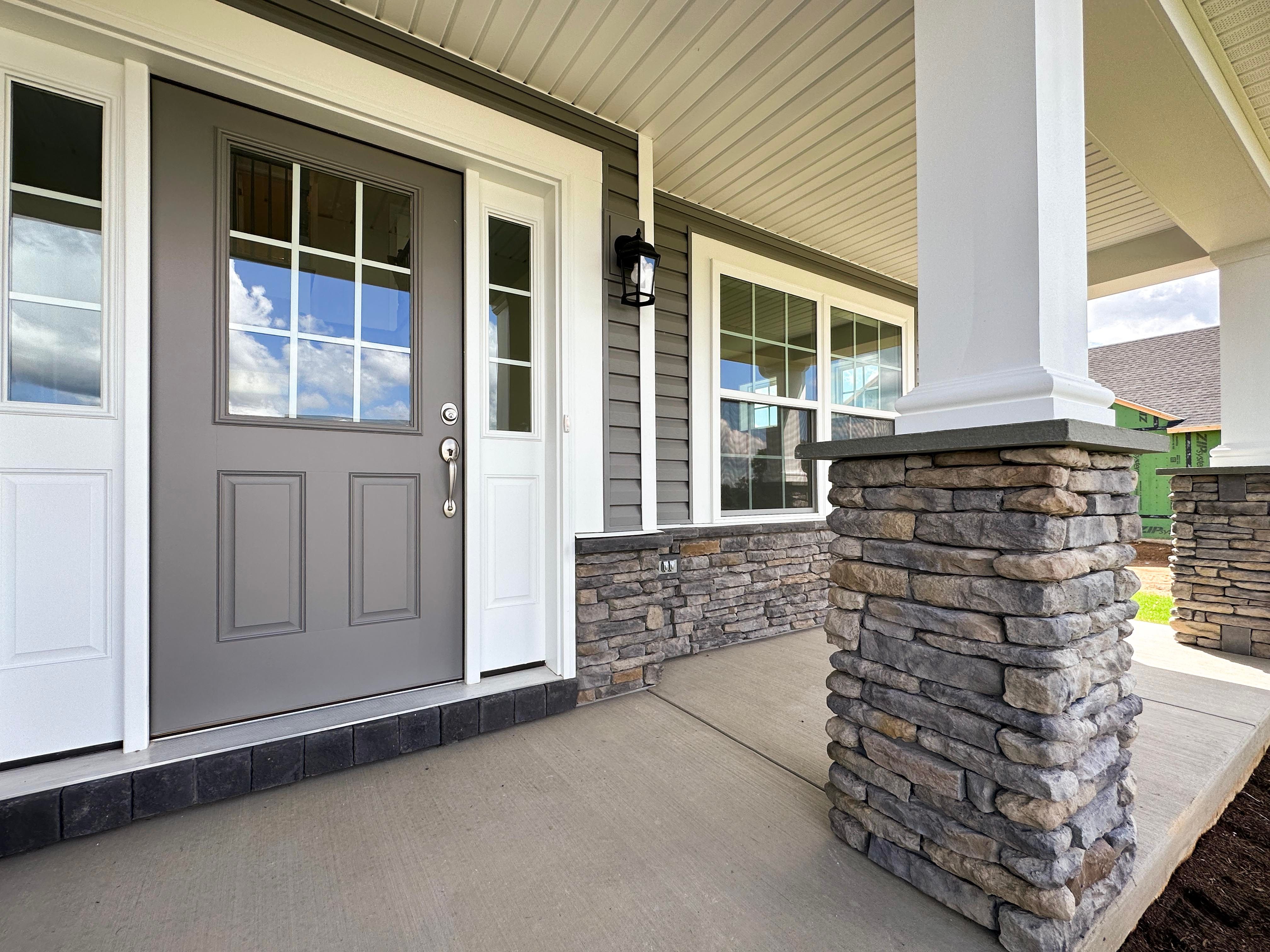 Front door with exterior light - white column with accent stone in foreground.
