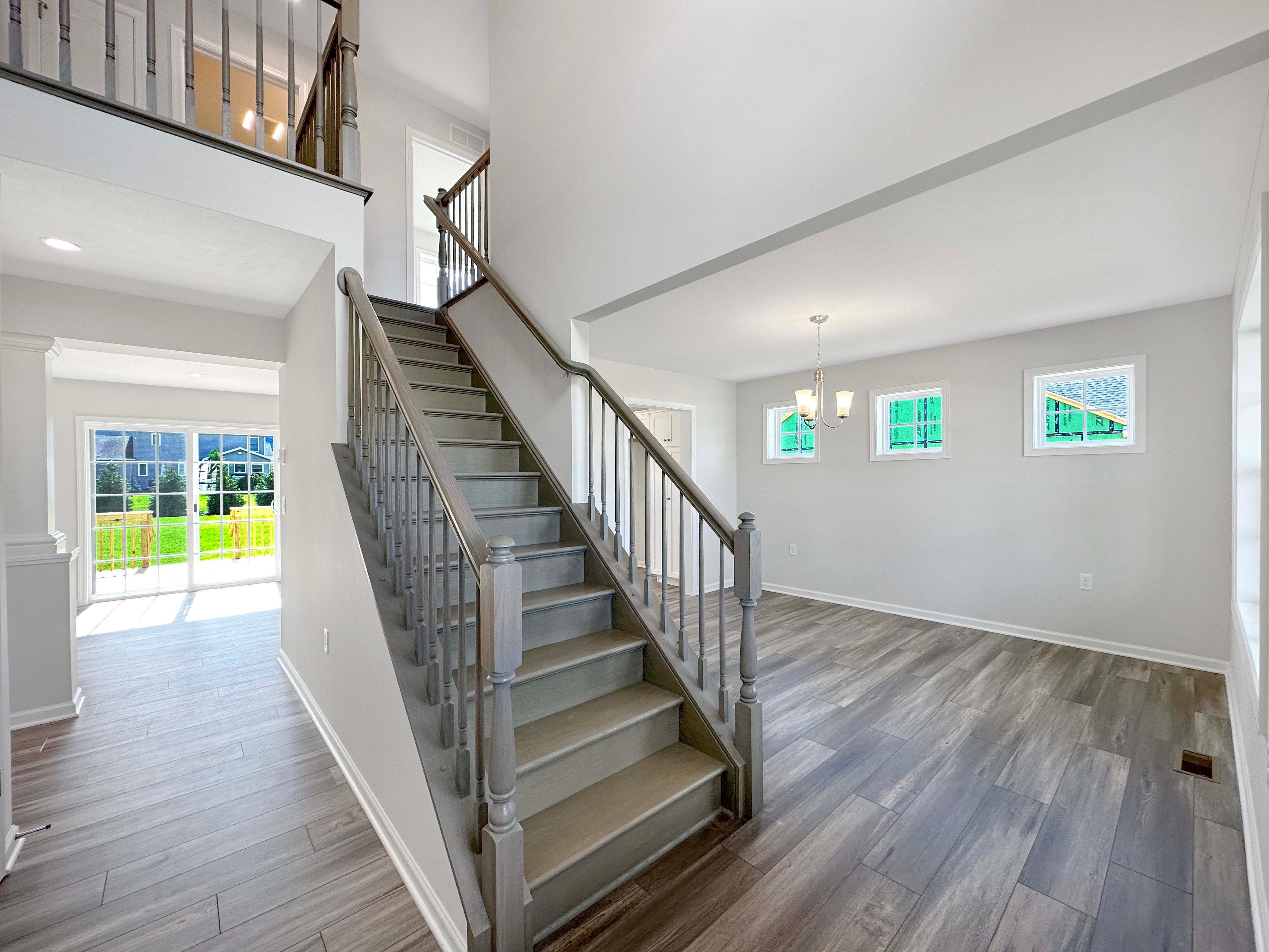 Side profile of staircase leading to 2nd floor, showing dining area with three windows on rear wall.