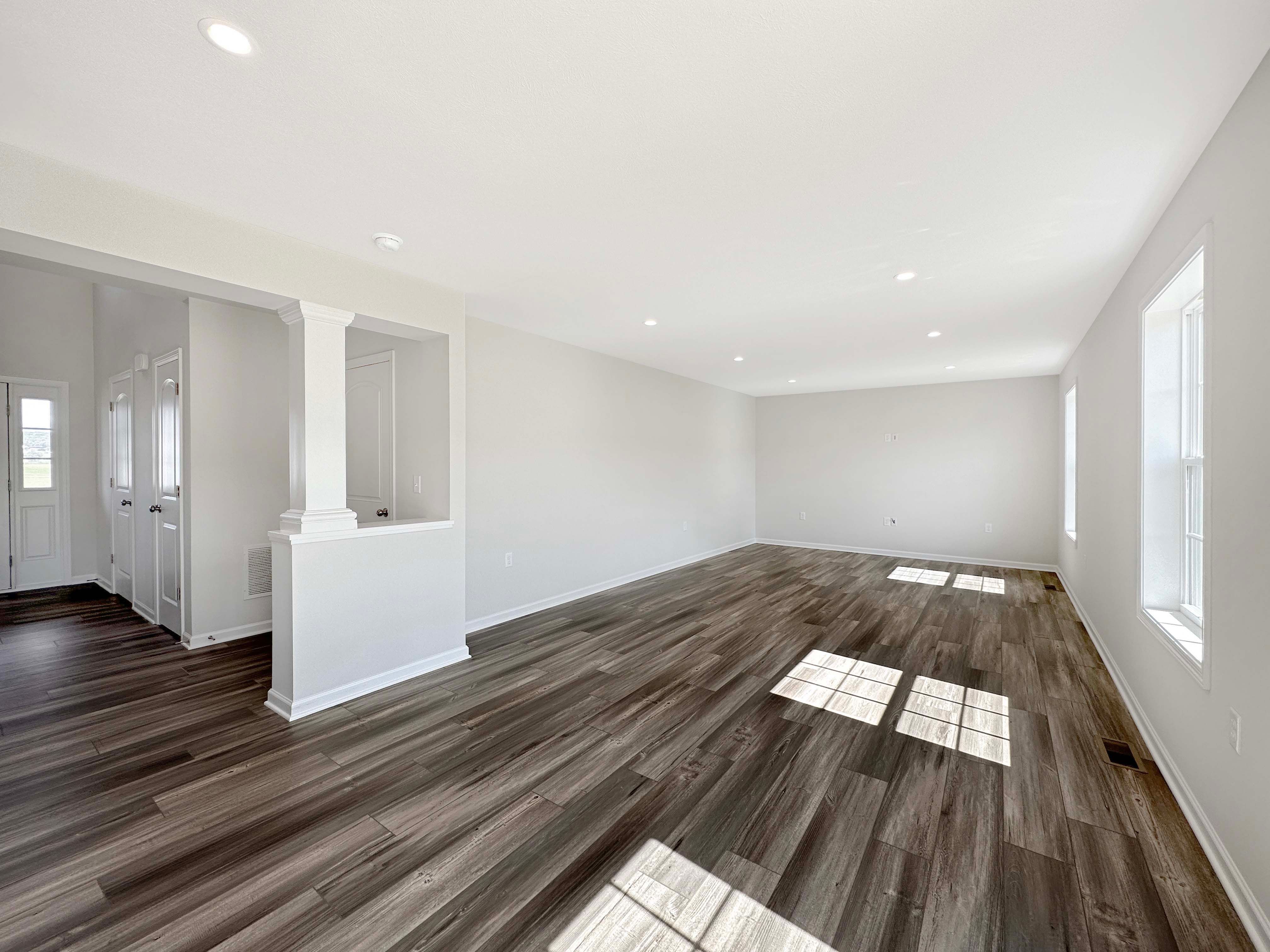 Family Room with LVT flooring and recessed lighting in ceiling - windows let in natural light.