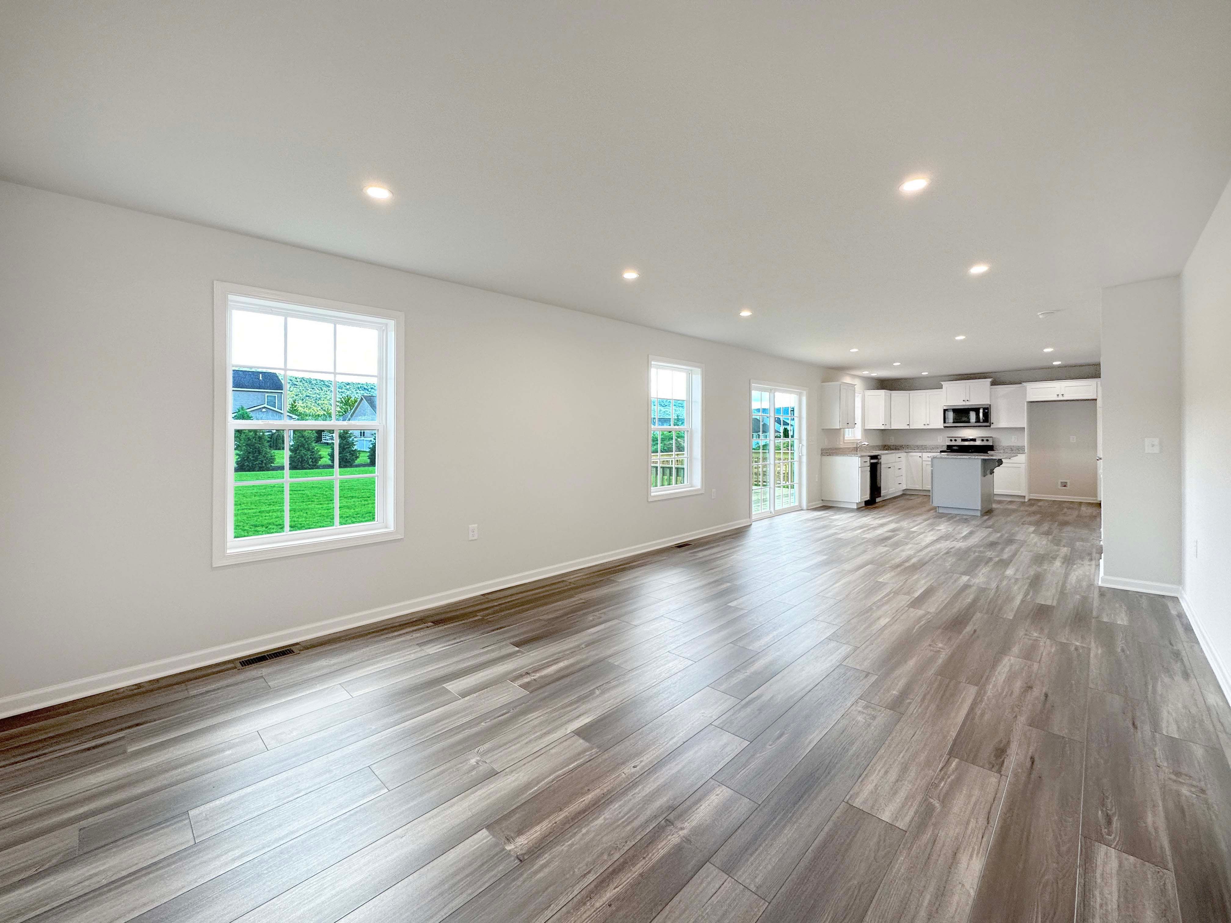 Family Room with LVT flooring, recessed lighting in ceiling, and two windows on left wall - facing towards the Kitchen.