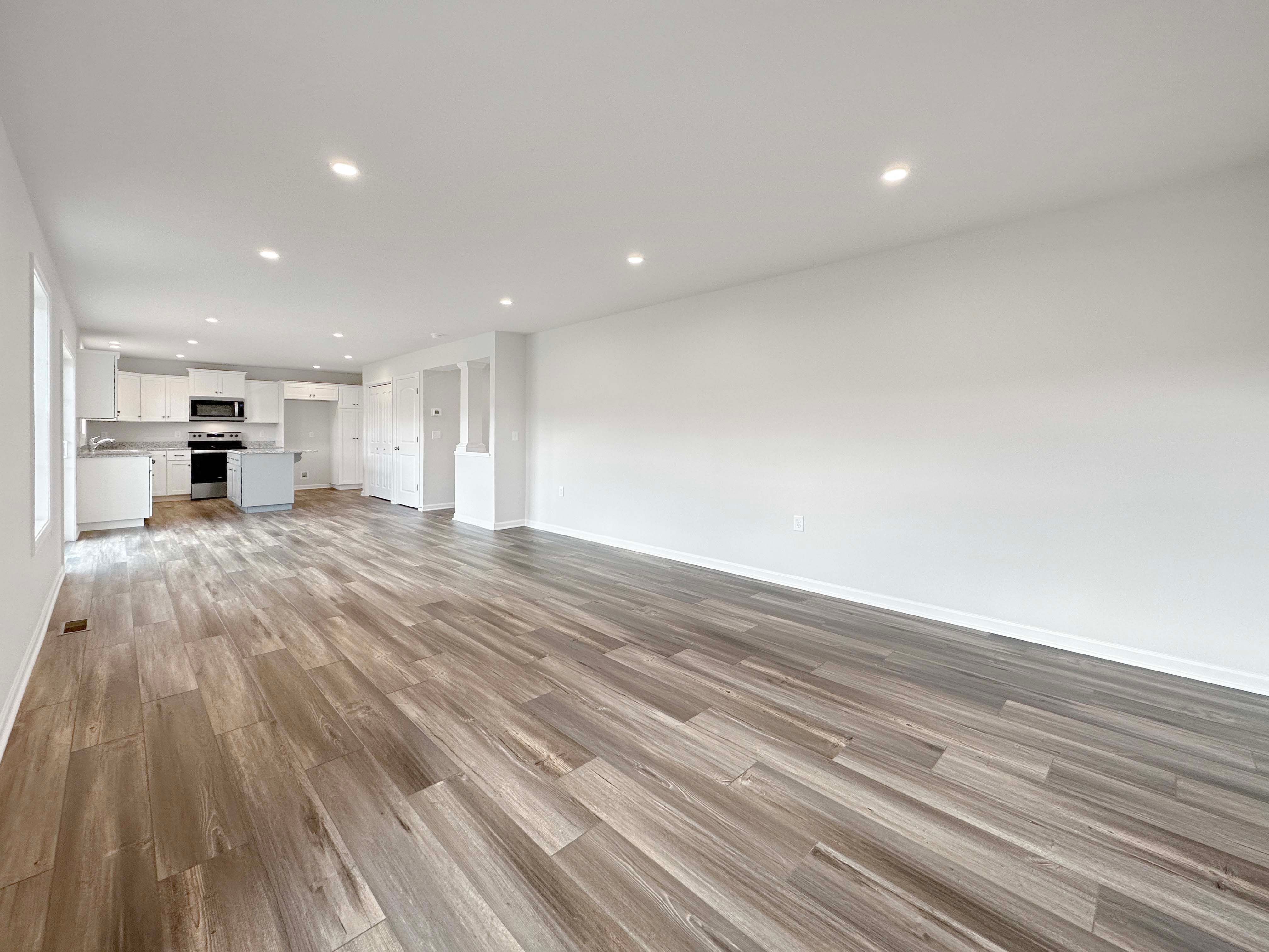 Family Room with LVT flooring and recessed lighting in ceiling- facing towards the Kitchen.