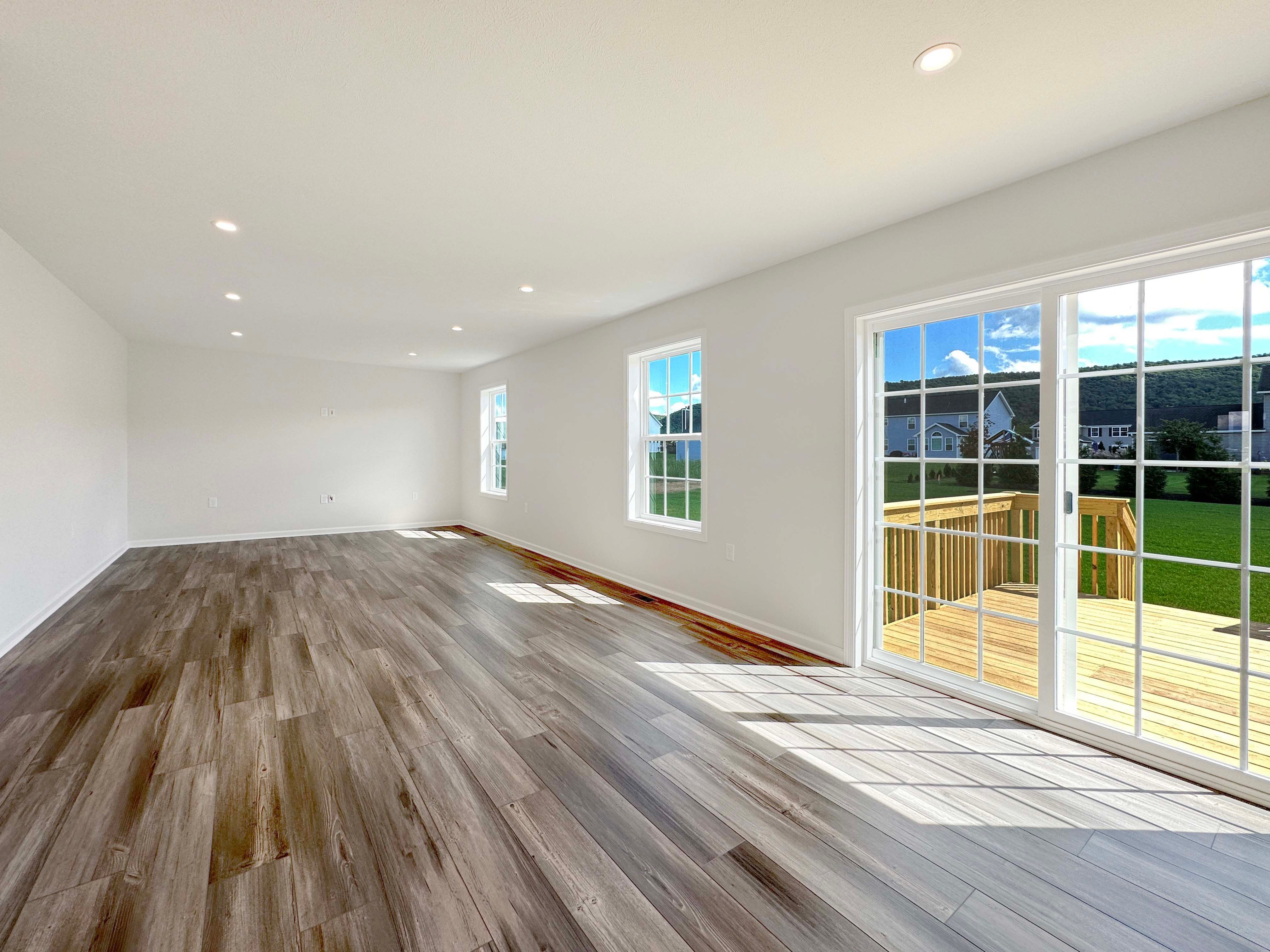 Family Room with LVT flooring, recessed lighting in ceiling, and two windows on left wall - facing towards the Kitchen.