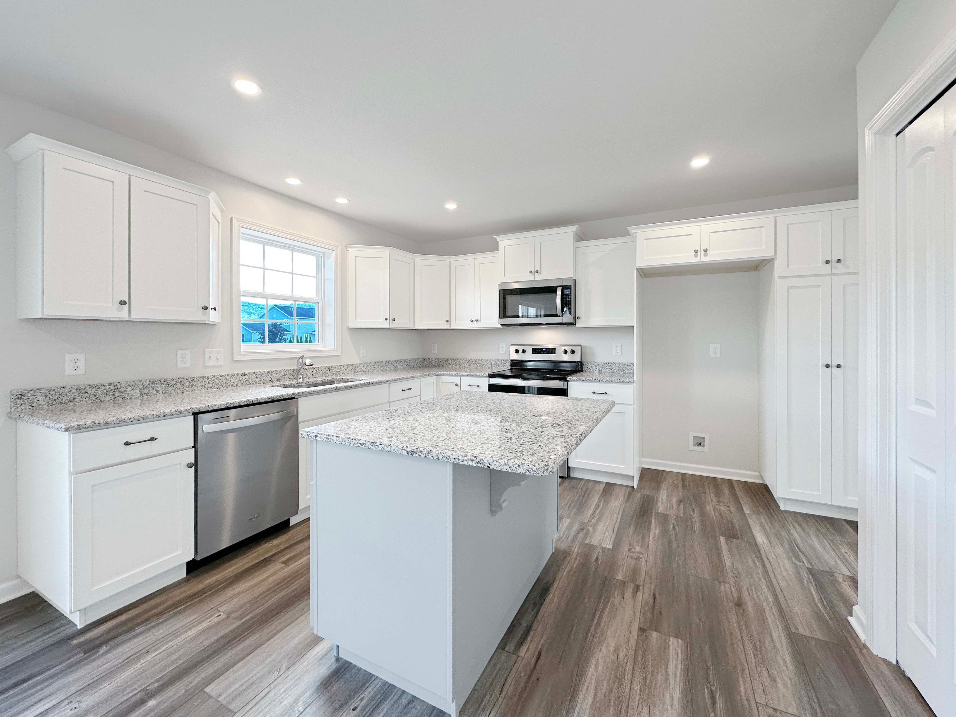 Kitchen with center island, white cabinetry, stainless appliances, and granite countertops.