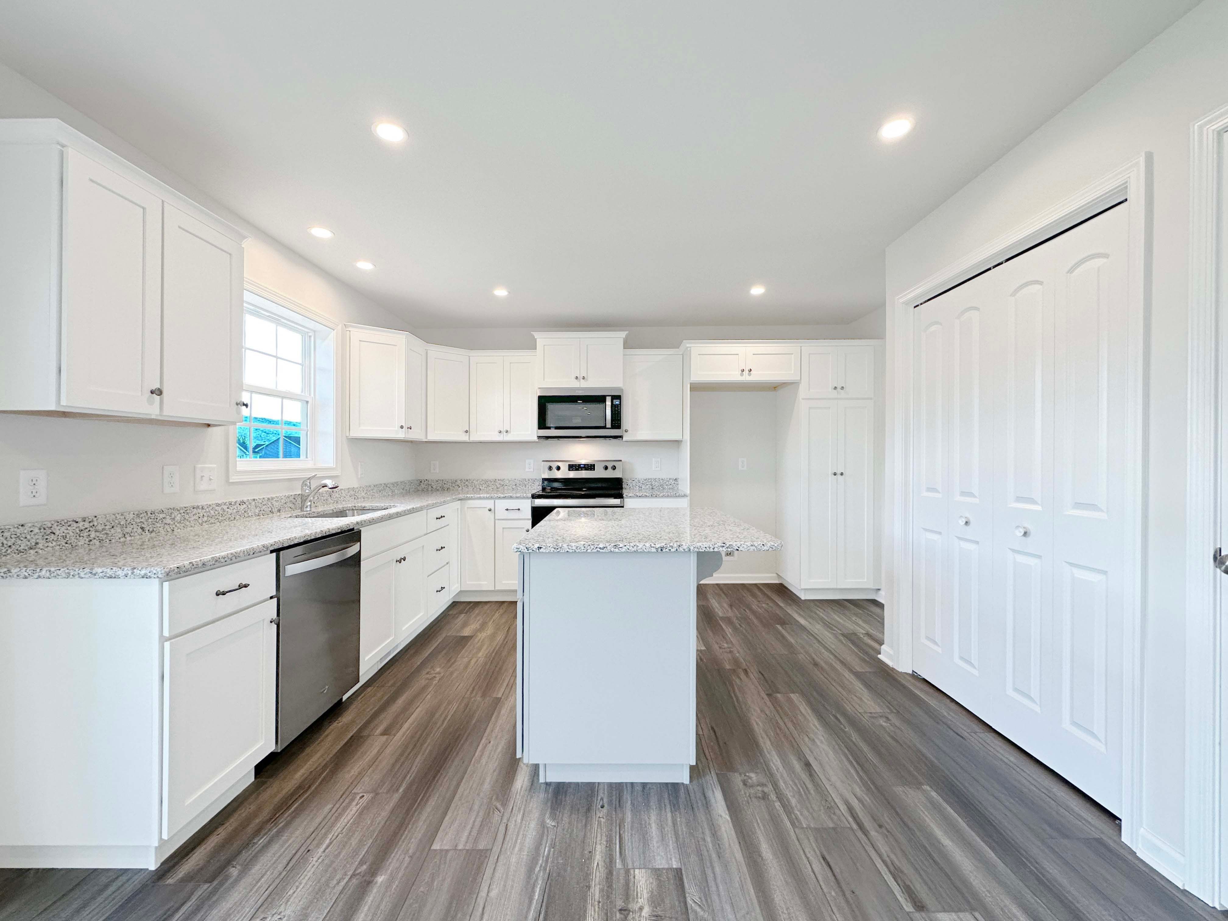 Kitchen with center island,white cabinetry, stainless appliances, and granite countertops.