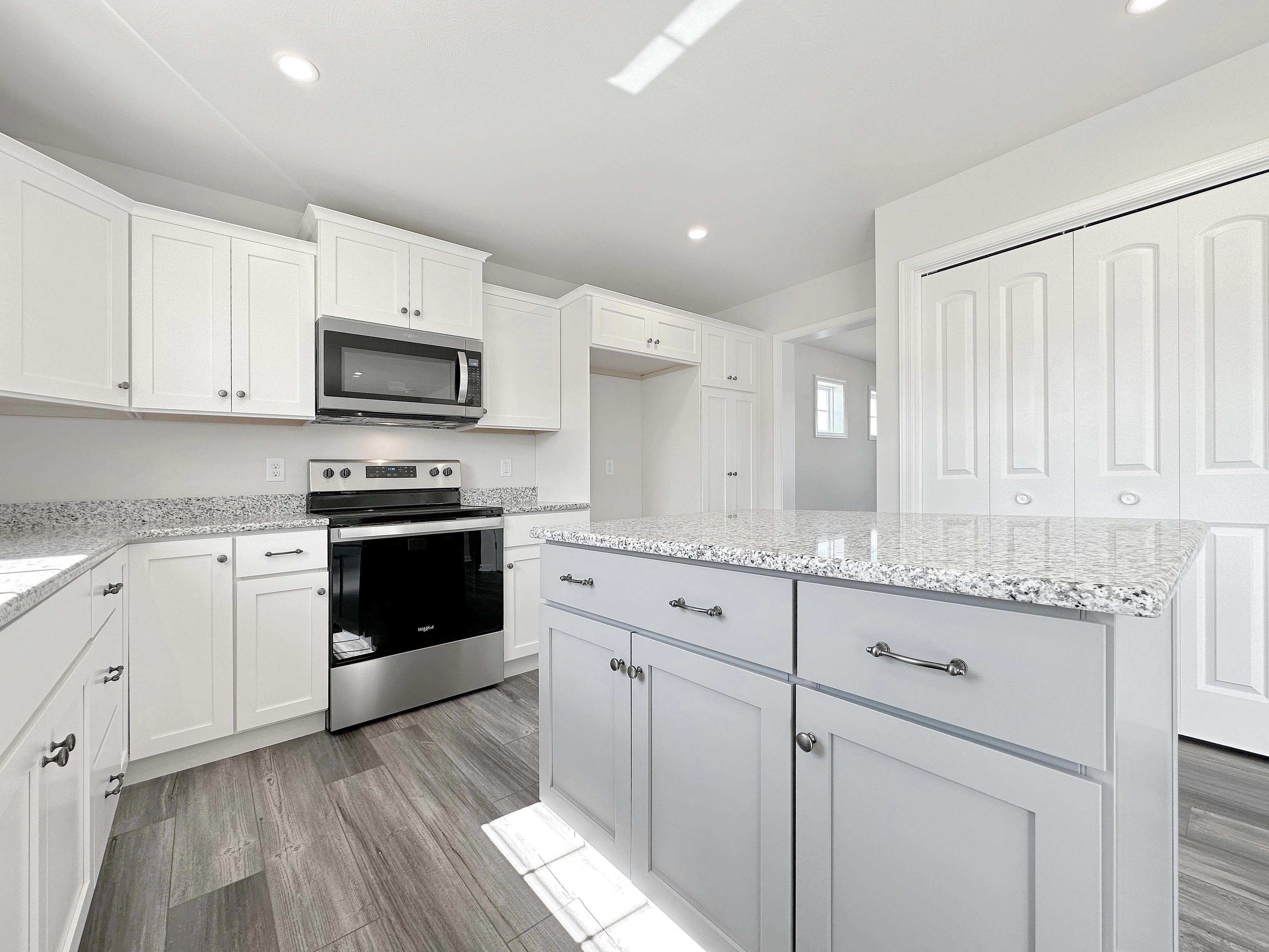 Kitchen with center island, white cabinetry, stainless appliances, and granite countertops.