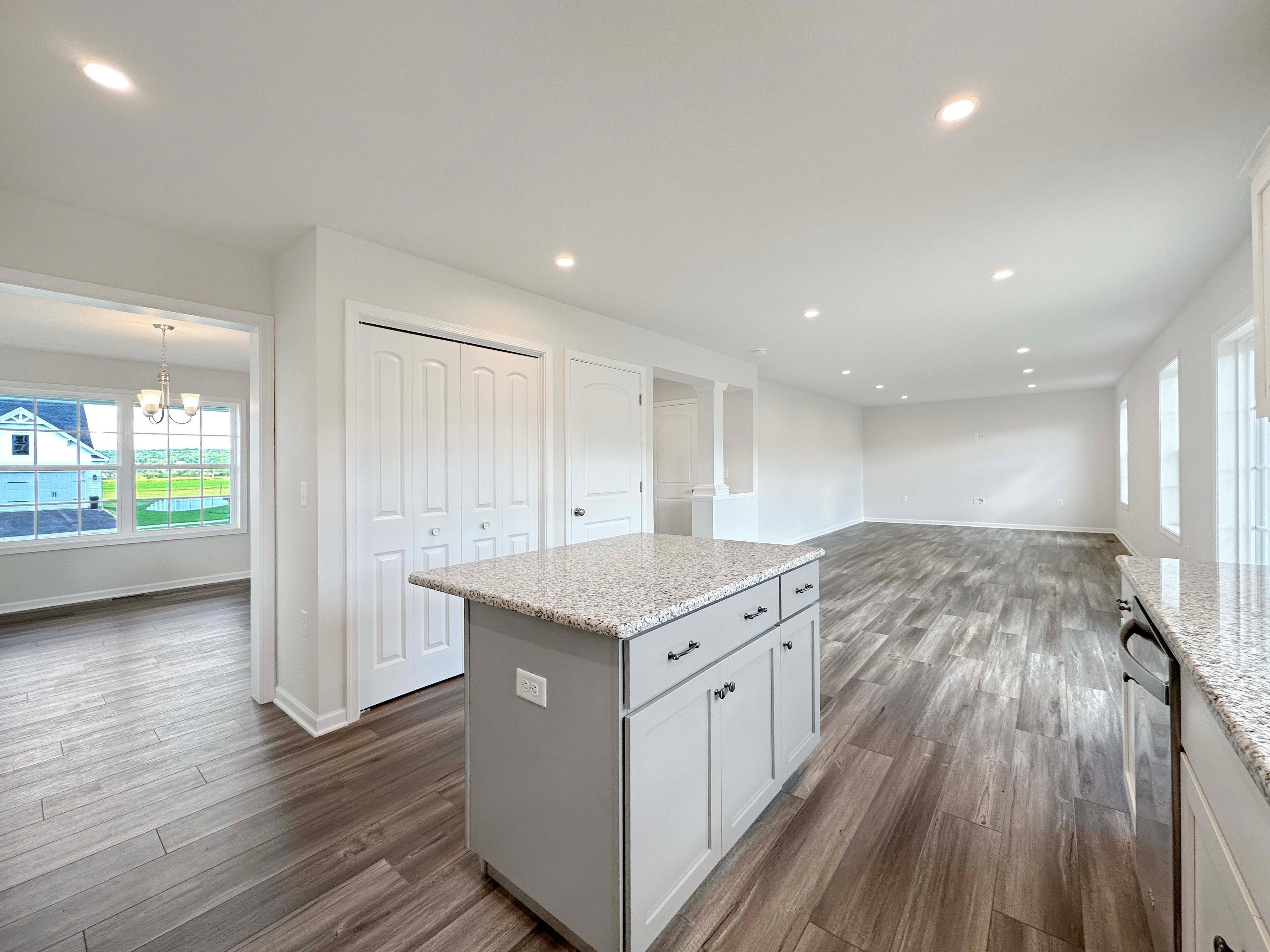 Kitchen center island with granite countertops. Far left entrance to dining room, far right Family Room in background.