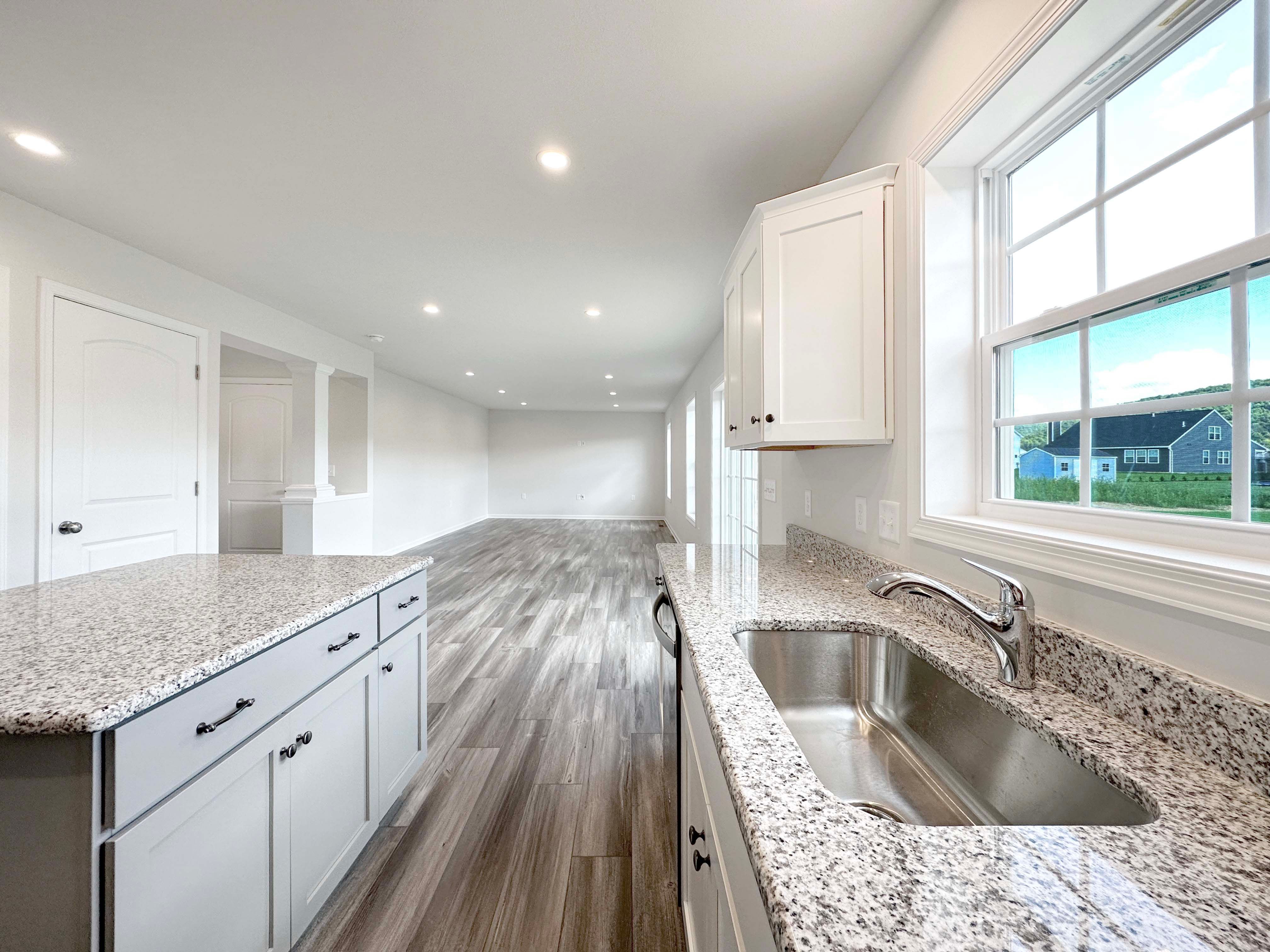Kitchen with center island, white cabinetry, and granite countertops - facing Family Room.
