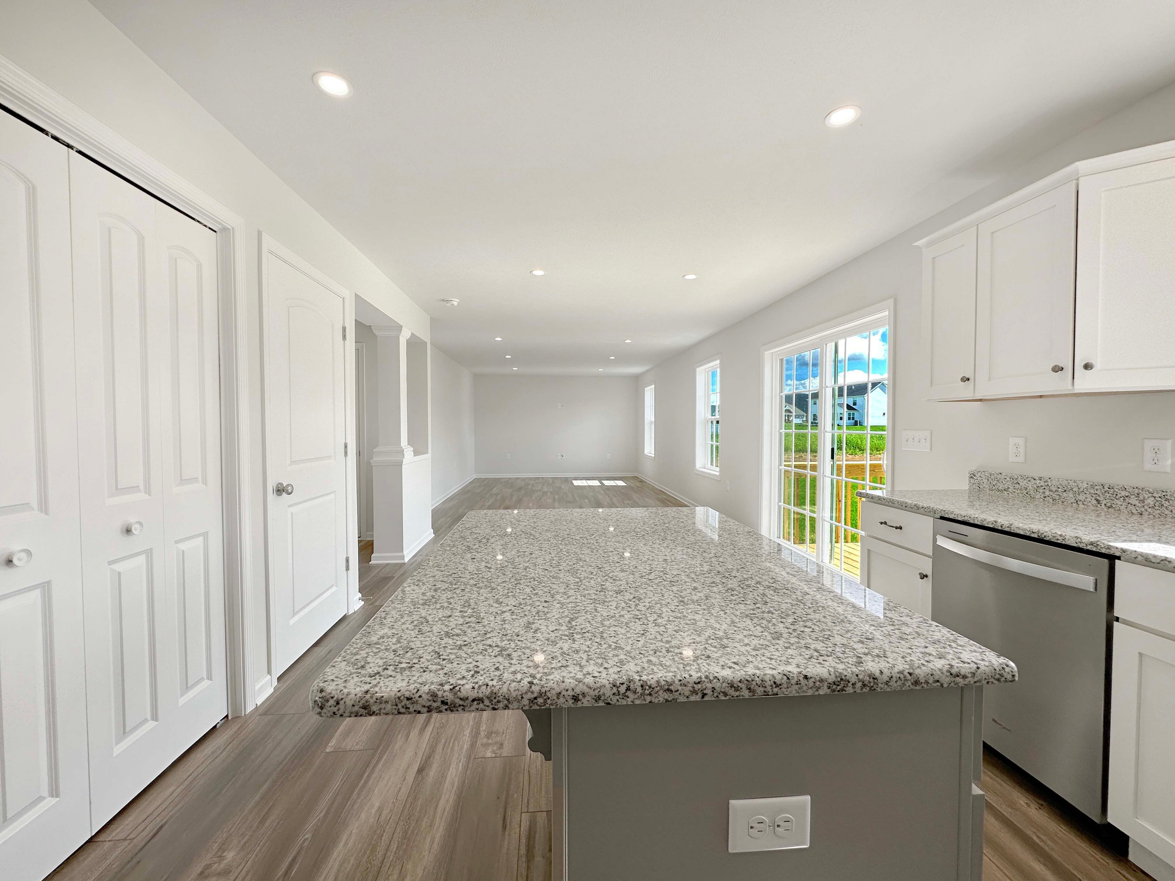 Kitchen with center island, white cabinetry, stainless dishwasher, and granite countertops - facing Family Room.