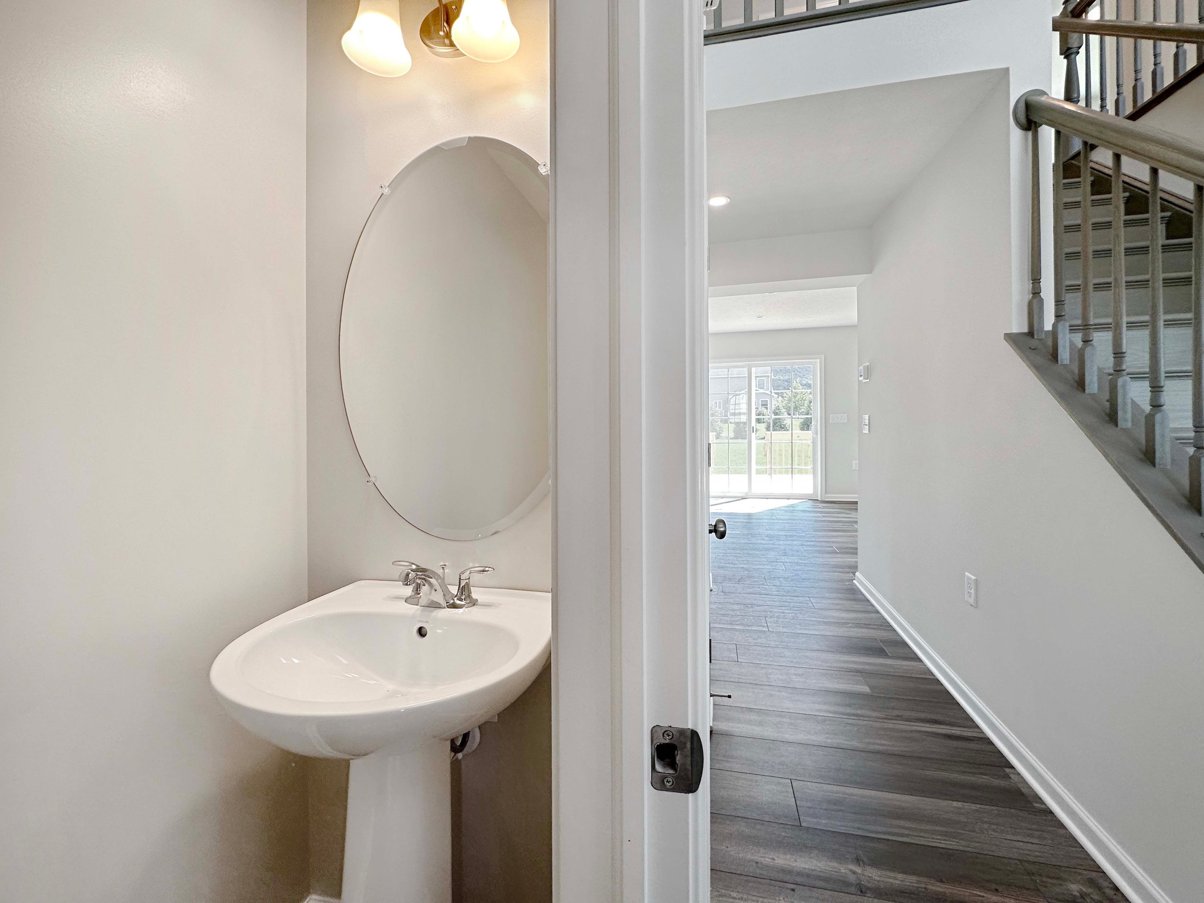 Powder room with pedestal sink and oval mirror, hallway to Family Room to the right.