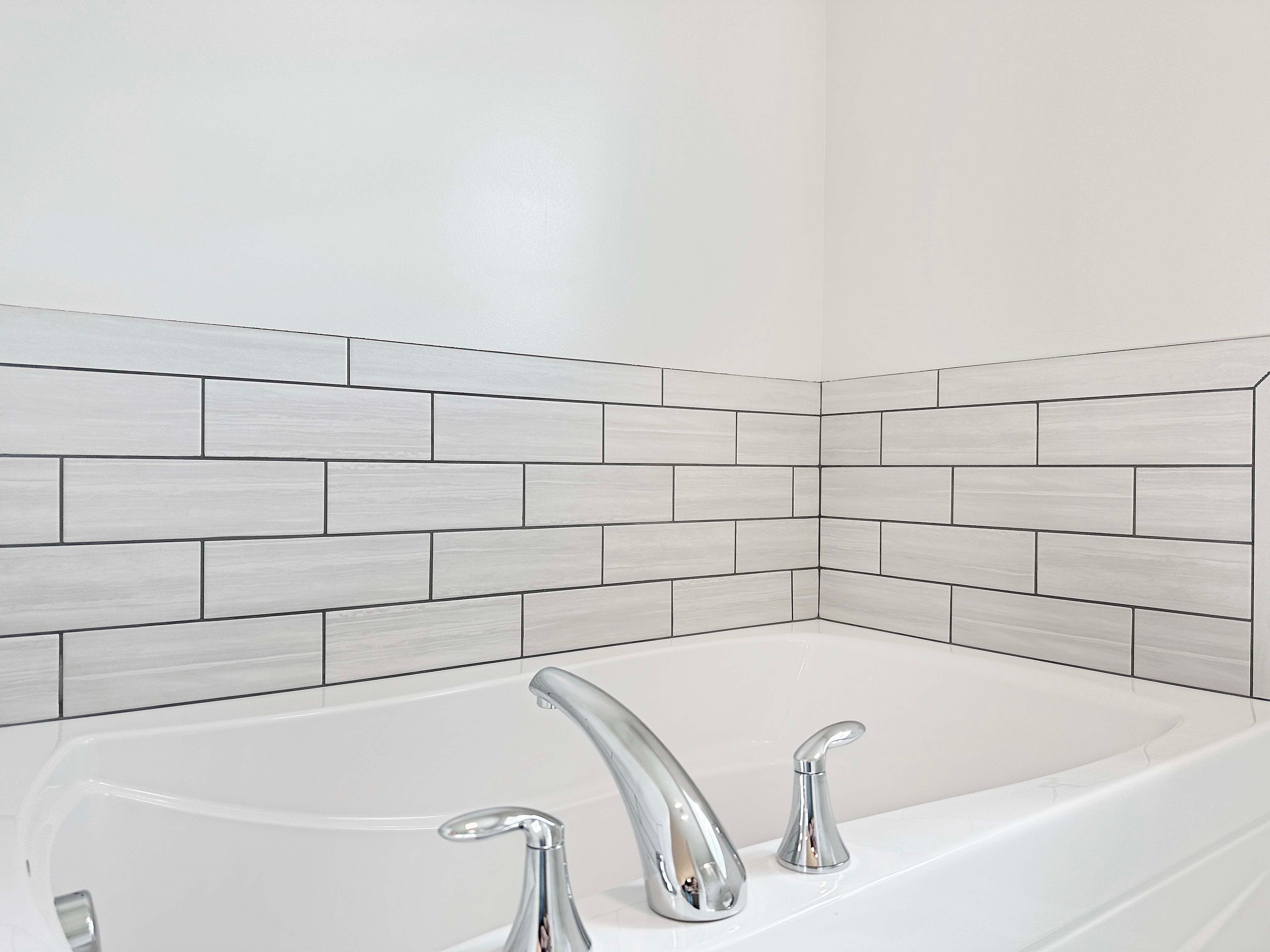 Owner's bathroom soaking tub with tile accent wall.