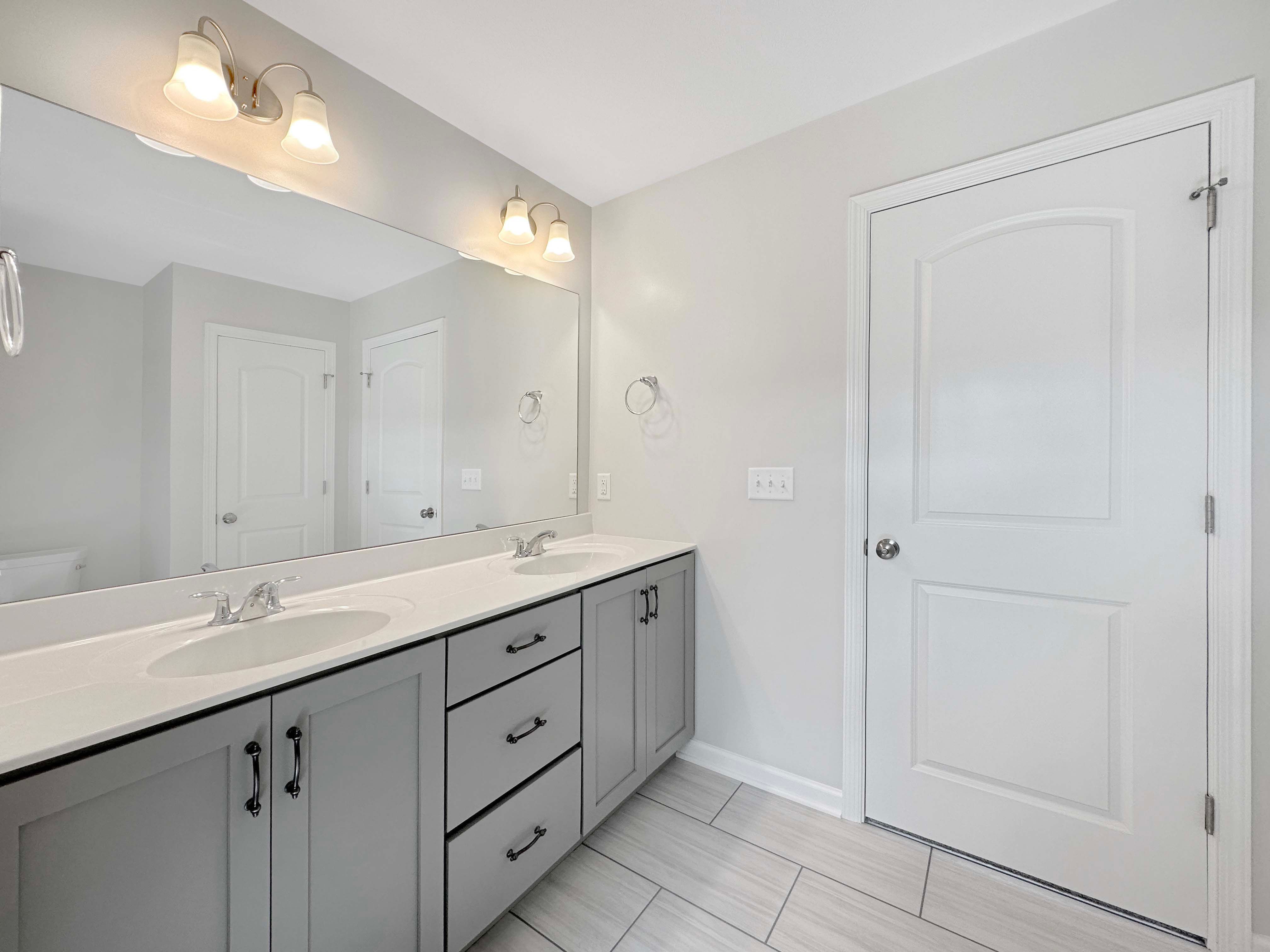 Secondary bathroom with ceramic tile flooring and grey cabinetry.