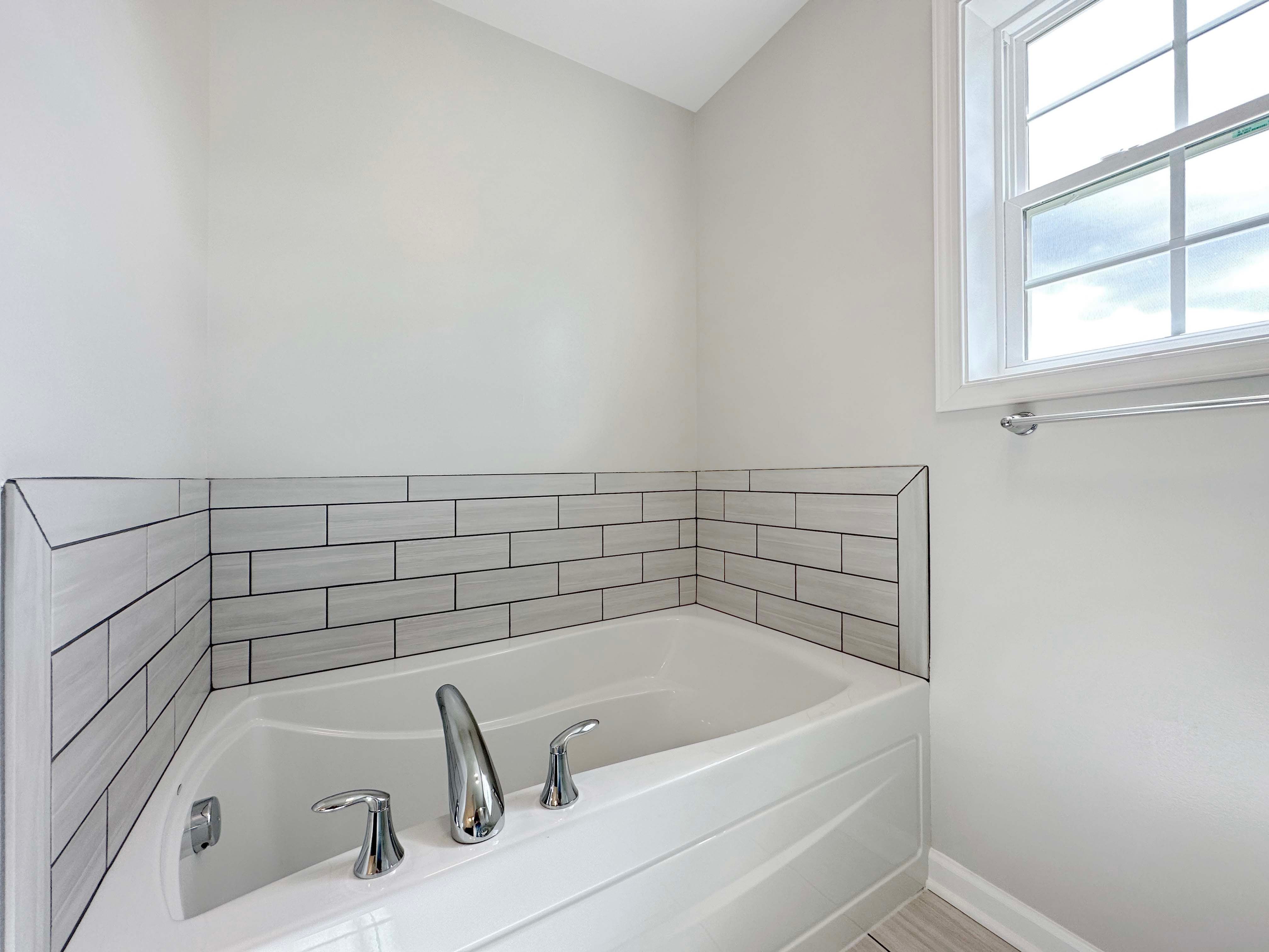 Owner's bathroom with ceramic tile flooring, and soaking tub with tile accent wall.