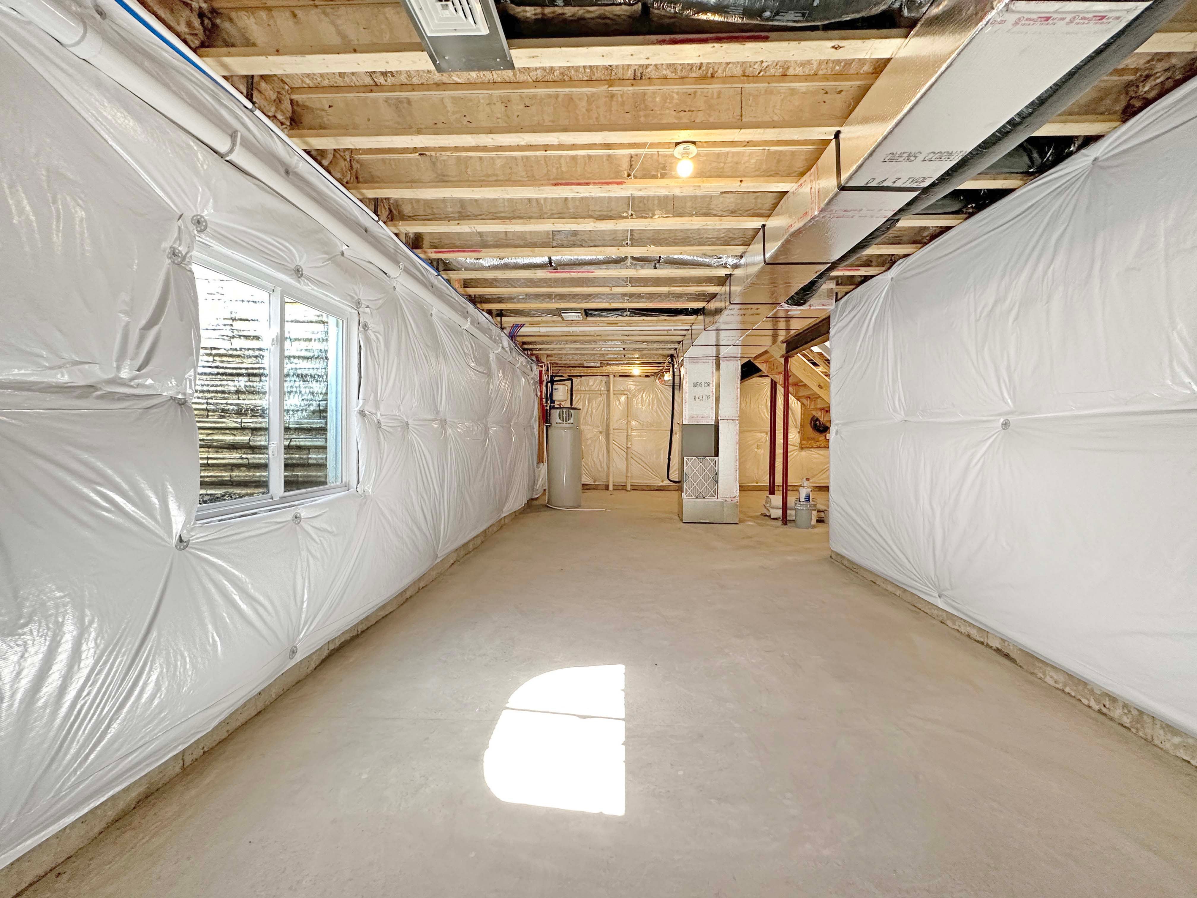 Unfinished Basement- concrete floor, I-joist floor system above, egress window well to left.