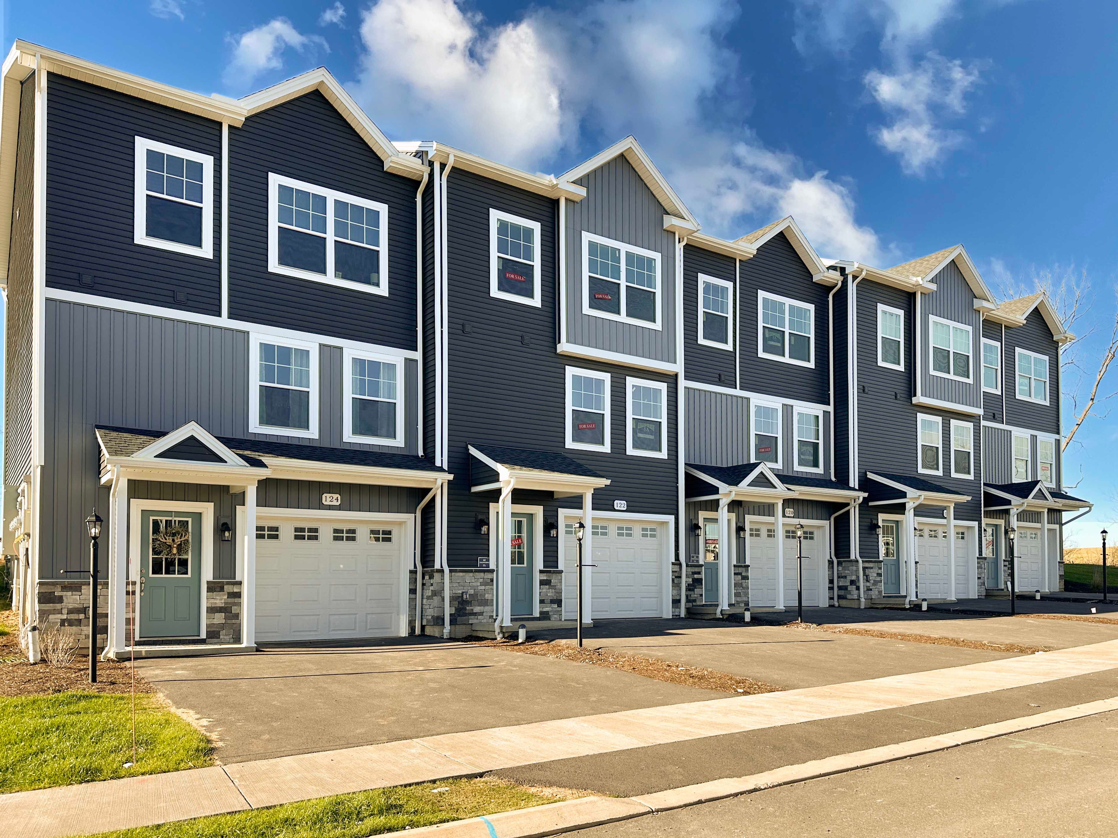3 story townhome with vinyl siding, covered front entry, and one car garage.