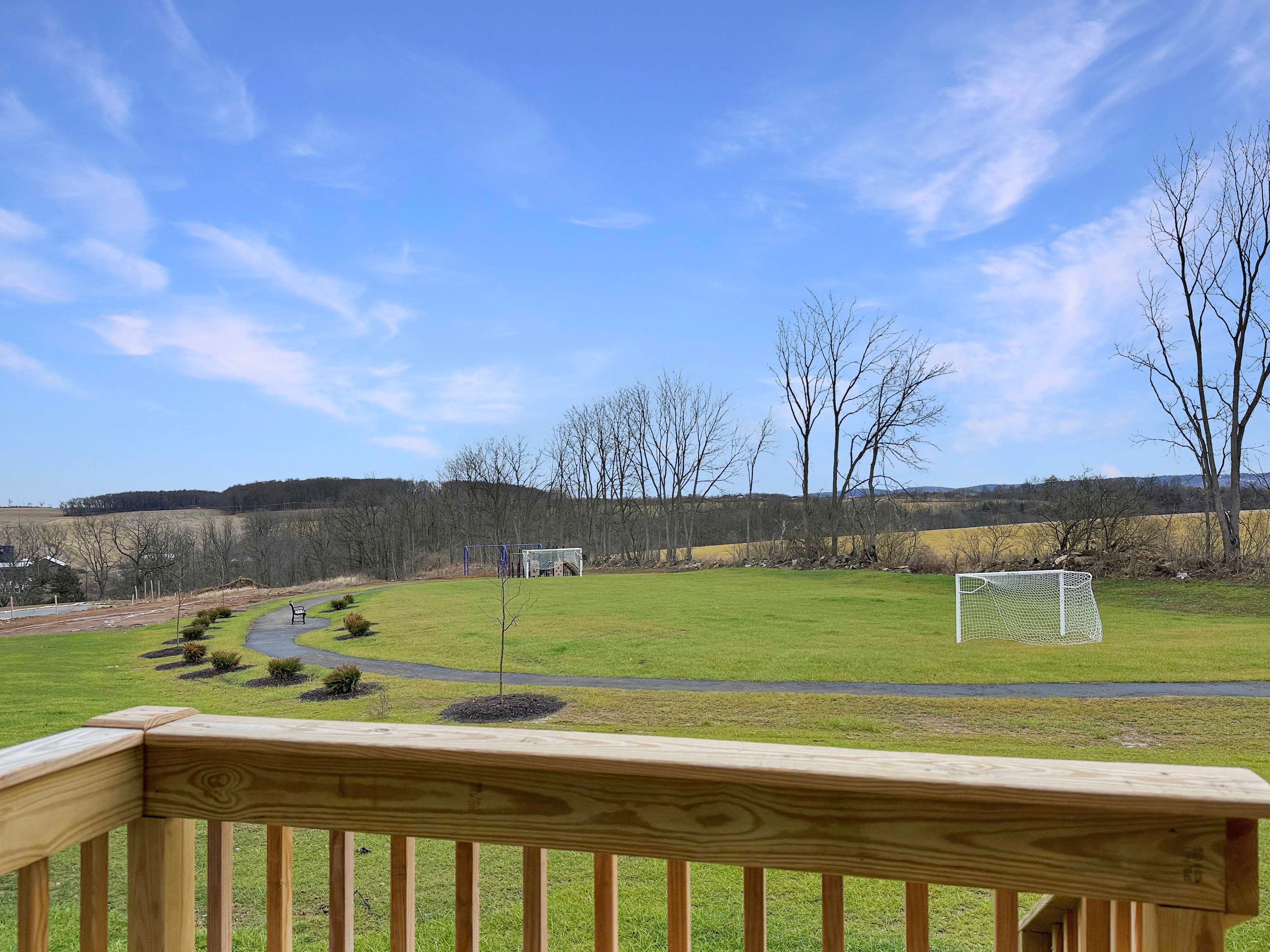 Rear deck rail overlooking paved trails with benches, and soccer fields